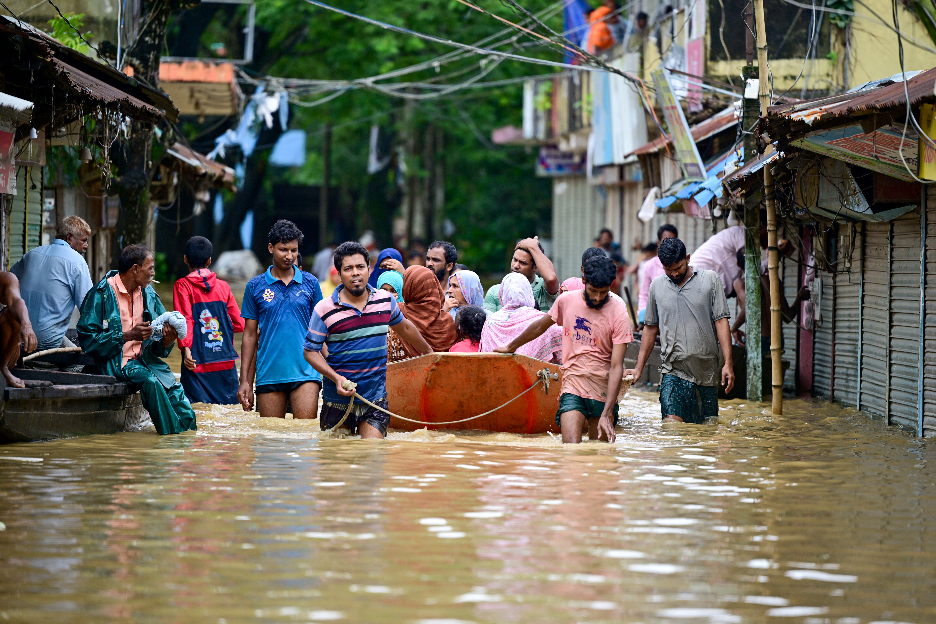 People wade through flood waters in Feni