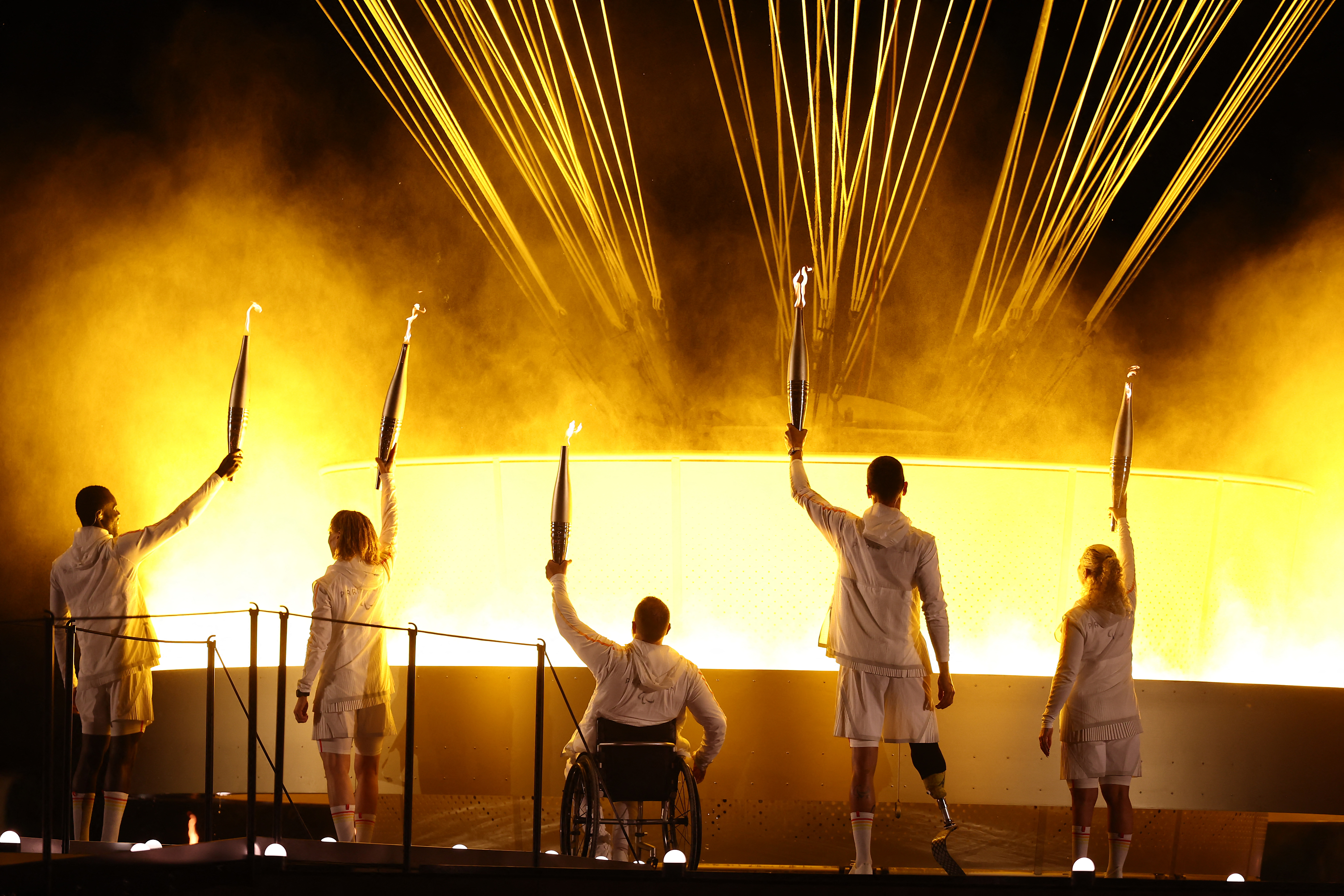 LtoR, France's paralympic torchbearers, Charles-Antoine Kaoukou, Nantenin Keita, Fabien Lamirault, Alexis Hanquinquant and Elodie Lorandi hold the Paralympic flame in front of the Paralympic cauldron during the Paris 2024 Paralympic Games Opening Ceremony at the Jardin des Tuileries (Tuileries Garden) in Paris on August 28, 2024. (Photo by Franck FIFE / AFP)