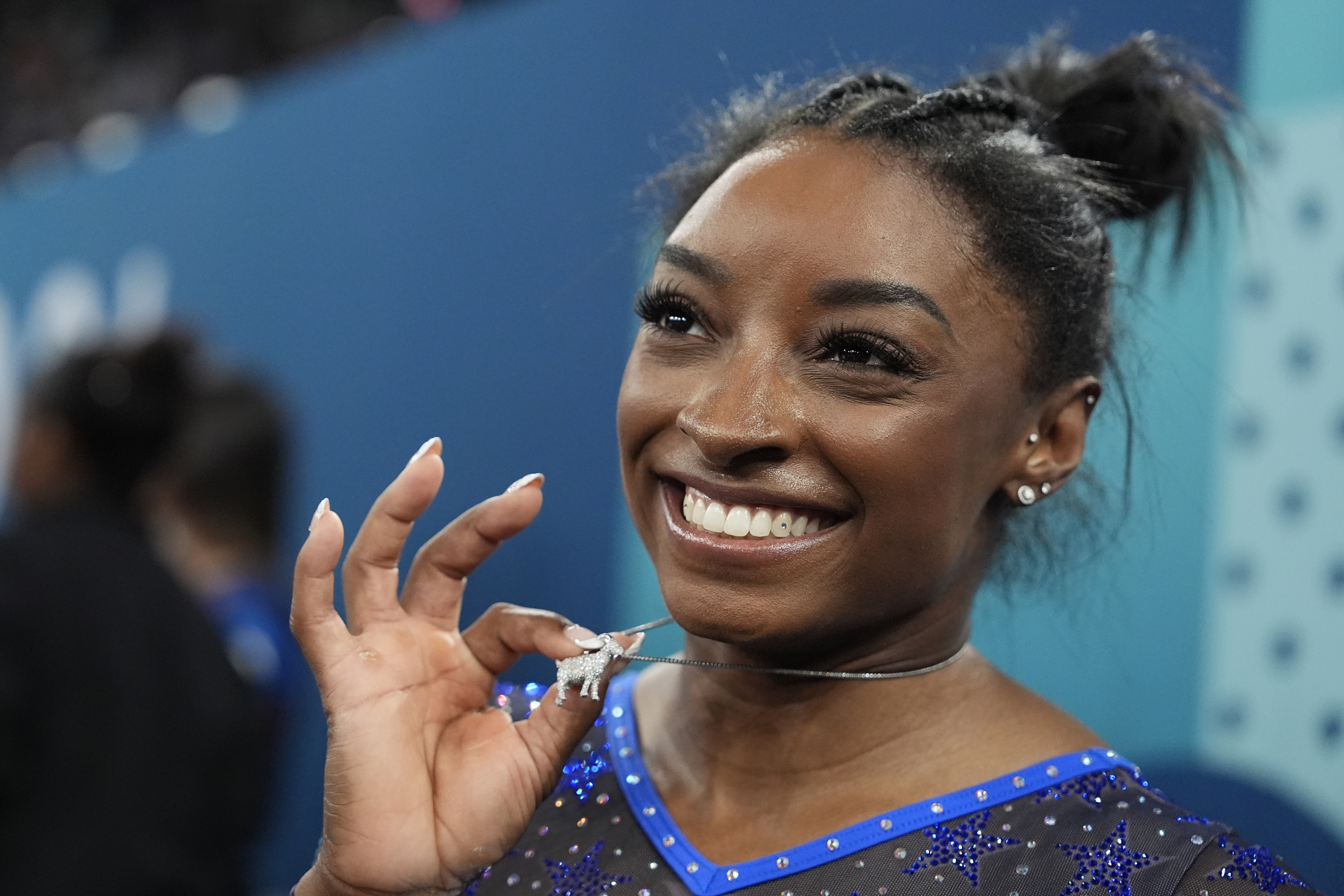 Simone Biles, of the United States, celebrates with her GOAT necklace after winning the gold medal during the women's artistic gymnastics all-around finals in Bercy Arena at the 2024 Summer Olympics, Thursday, Aug. 1, 2024, in Paris, France. (AP Photo/Charlie Riedel)