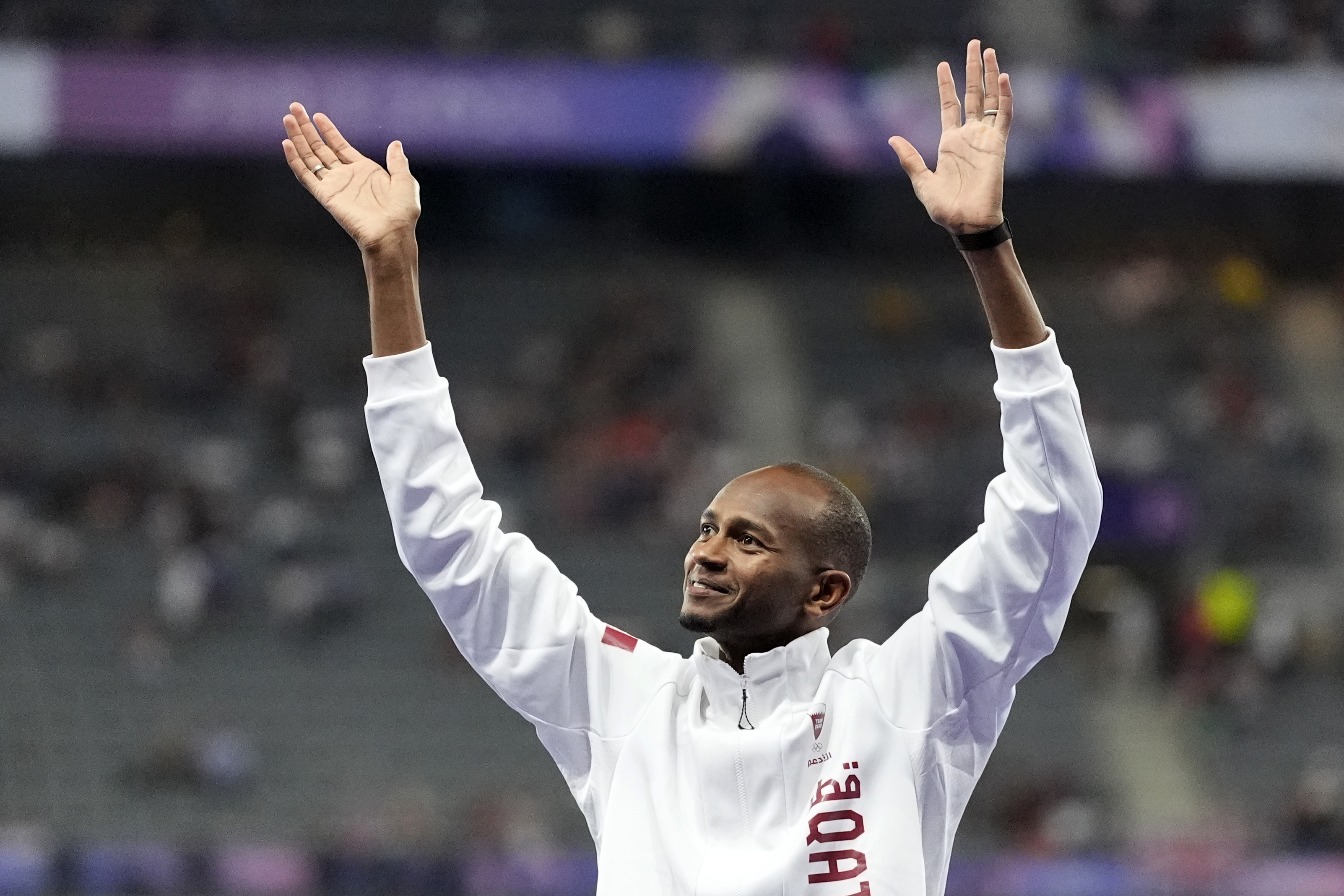 Men's high jump bronze medalist Mutaz Essa Barshim, of Qatar, waves on the podium, at the 2024 Summer Olympics, Saturday, Aug. 10, 2024, in Saint-Denis, France. (AP Photo/Matthias Schrader)