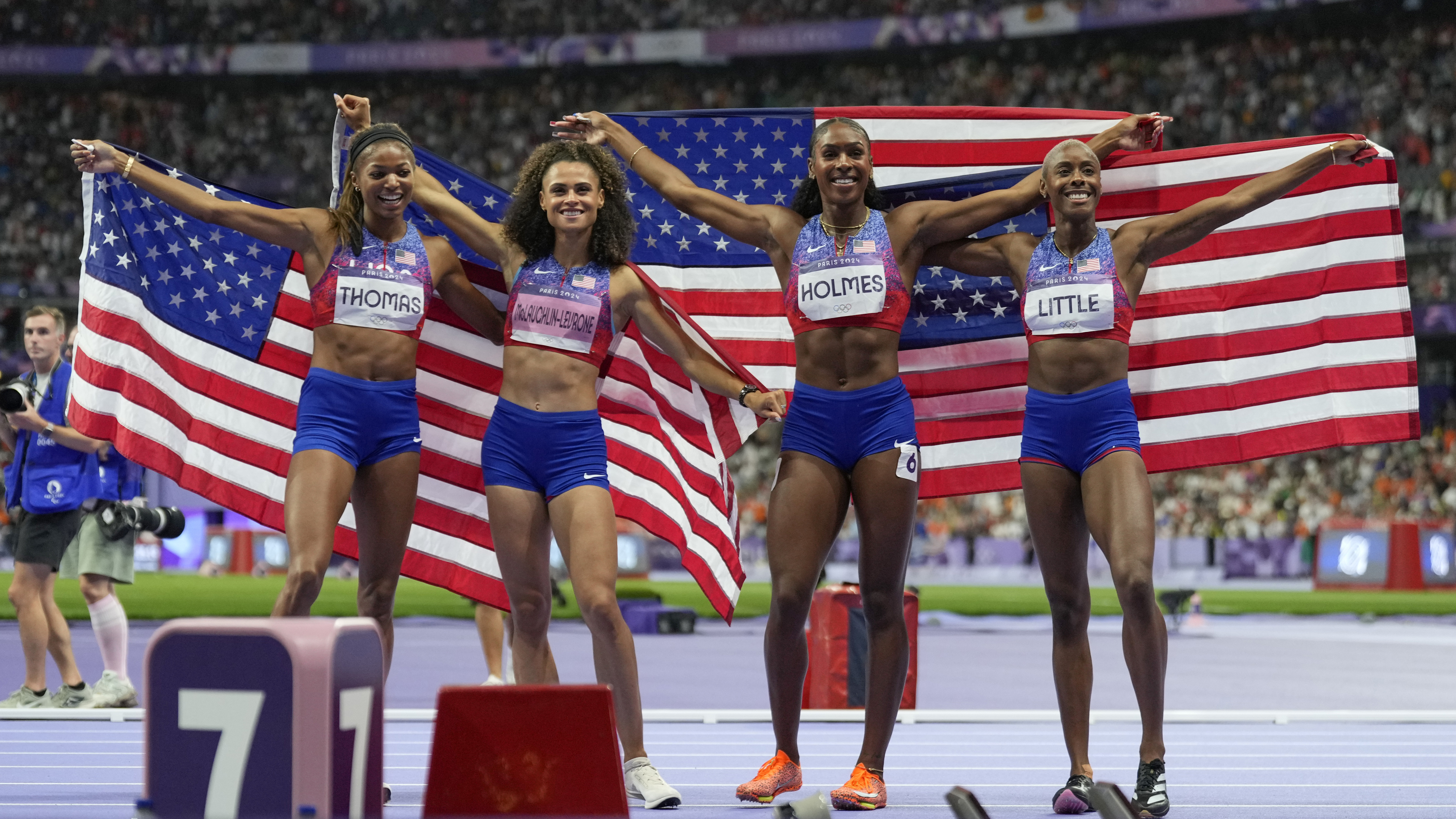 Gabby Thomas, Sydney Michelle McLaughlin, Alexis Holmes and Shamier Little, of the United States, pose after winning the gold medal in the women's 4 x 400 meters relay final at the 2024 Summer Olympics, Saturday, Aug. 10, 2024, in Saint-Denis, France. (AP Photo/Ashley Landis)