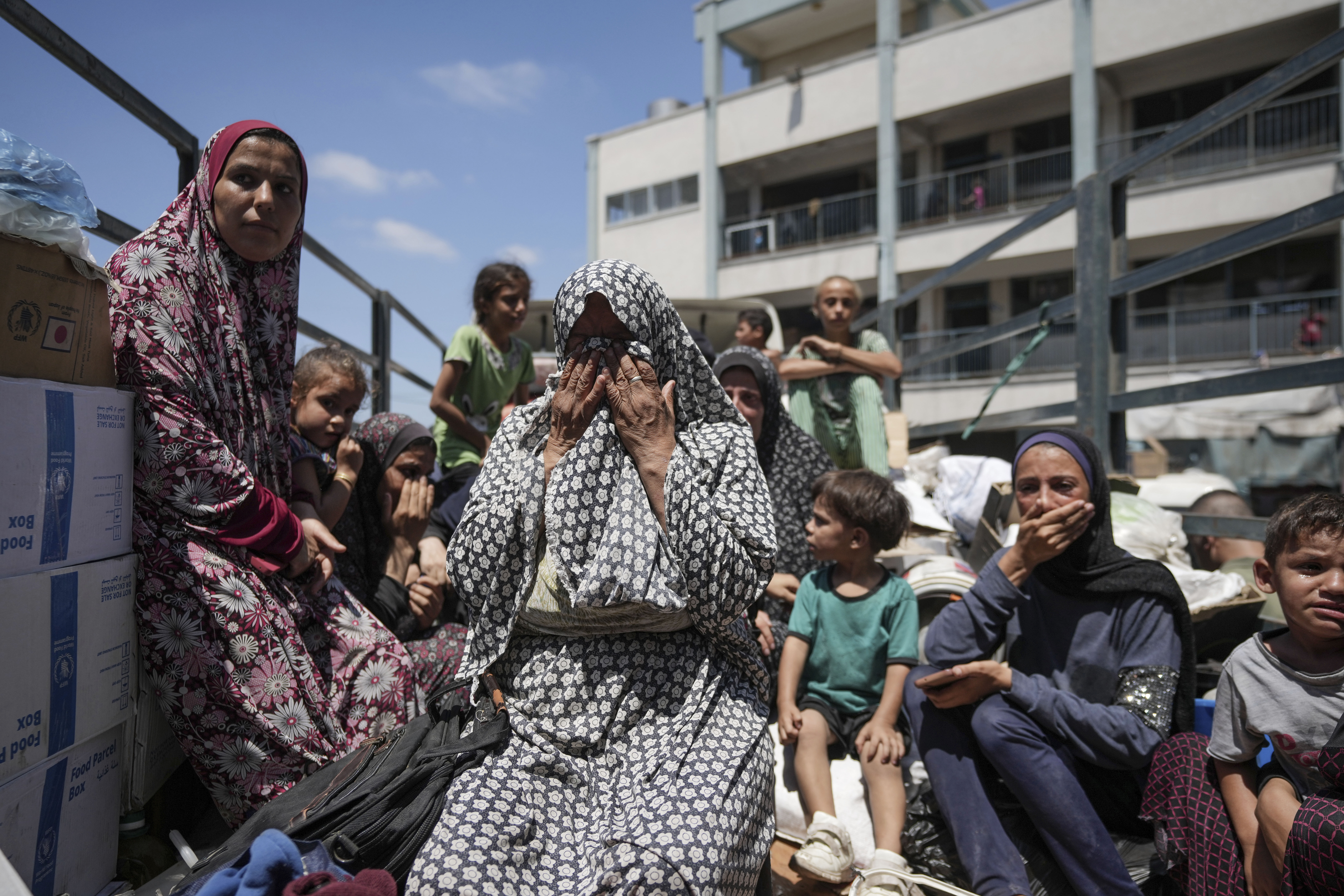Palestinian women weep on a truck as she evacuates a school that had been her shelter, in eastern Deir al-Balah, Gaza Strip, Friday, Aug. 16, 2024, after the Israeli military dropped leaflets asking civilians to evacuate from the area, saying forces plan to respond to rocket fire that targeted Israel. (AP Photo/Abdel Kareem Hana)