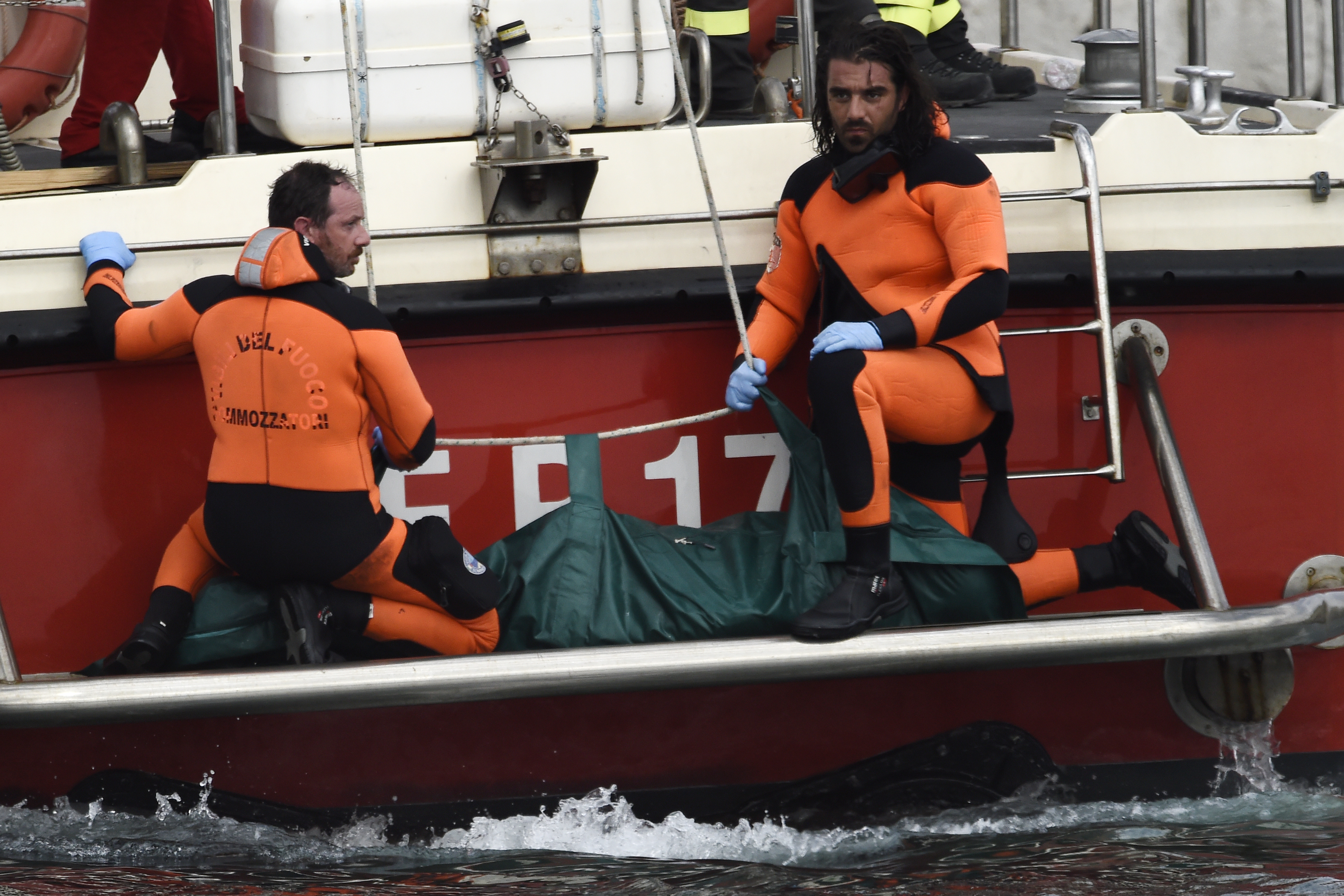 Italian Firefighters scuba divers bring ashore in a green bag the body of one of the victims of the UK flag vessel Bayesian, Wednesday, Aug. 21, 2024. The sail yacht was hit by a violent sudden storm and sunk early Monday, while at anchor off the Sicilian village of Porticello near Palermo, in southern Italy. (AP Photo/Salvatore Cavalli)
