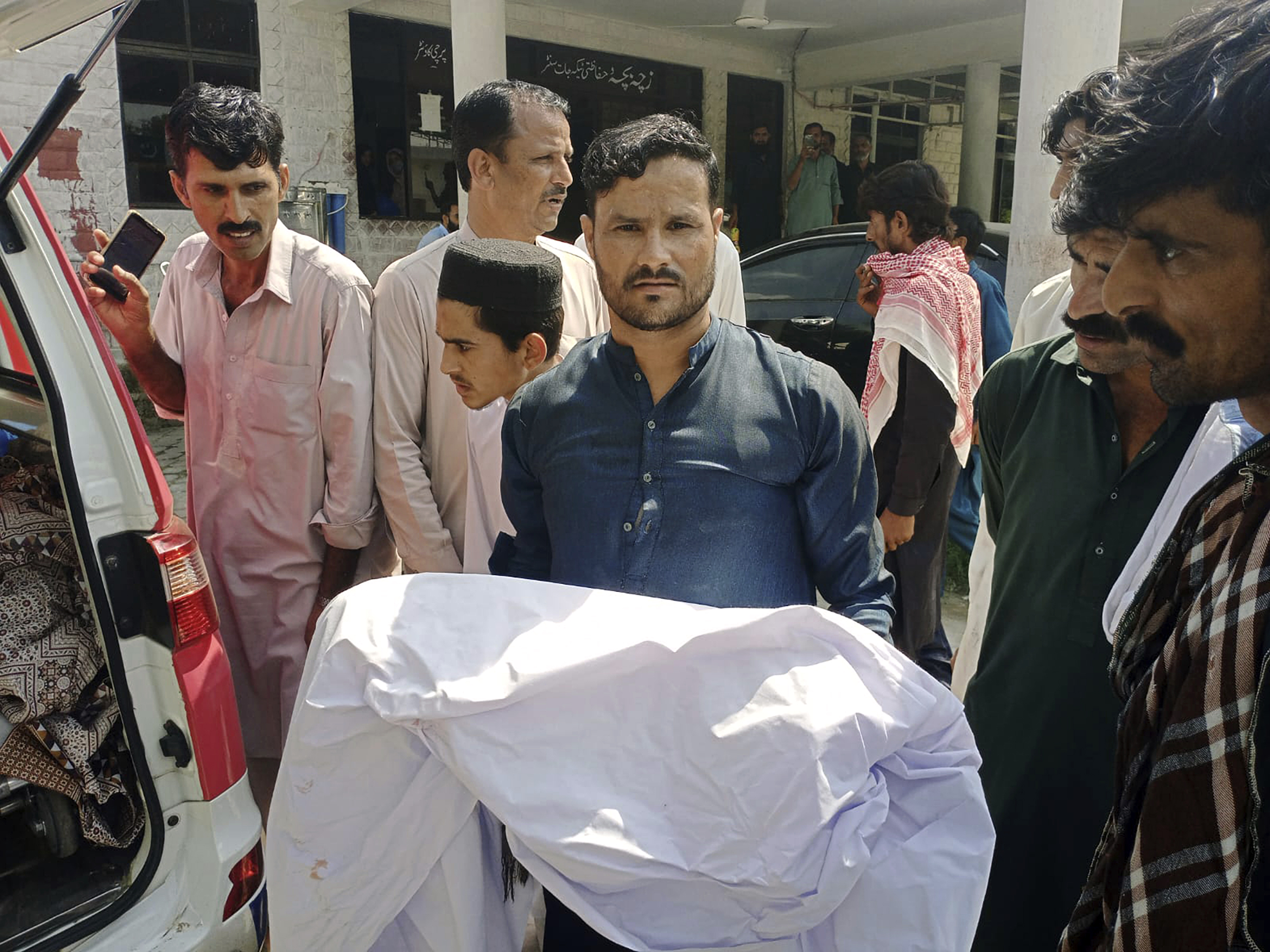 A relative carries body of a child, who was killed as a passenger bus fell into a ravine, at a hospital in Kahuta