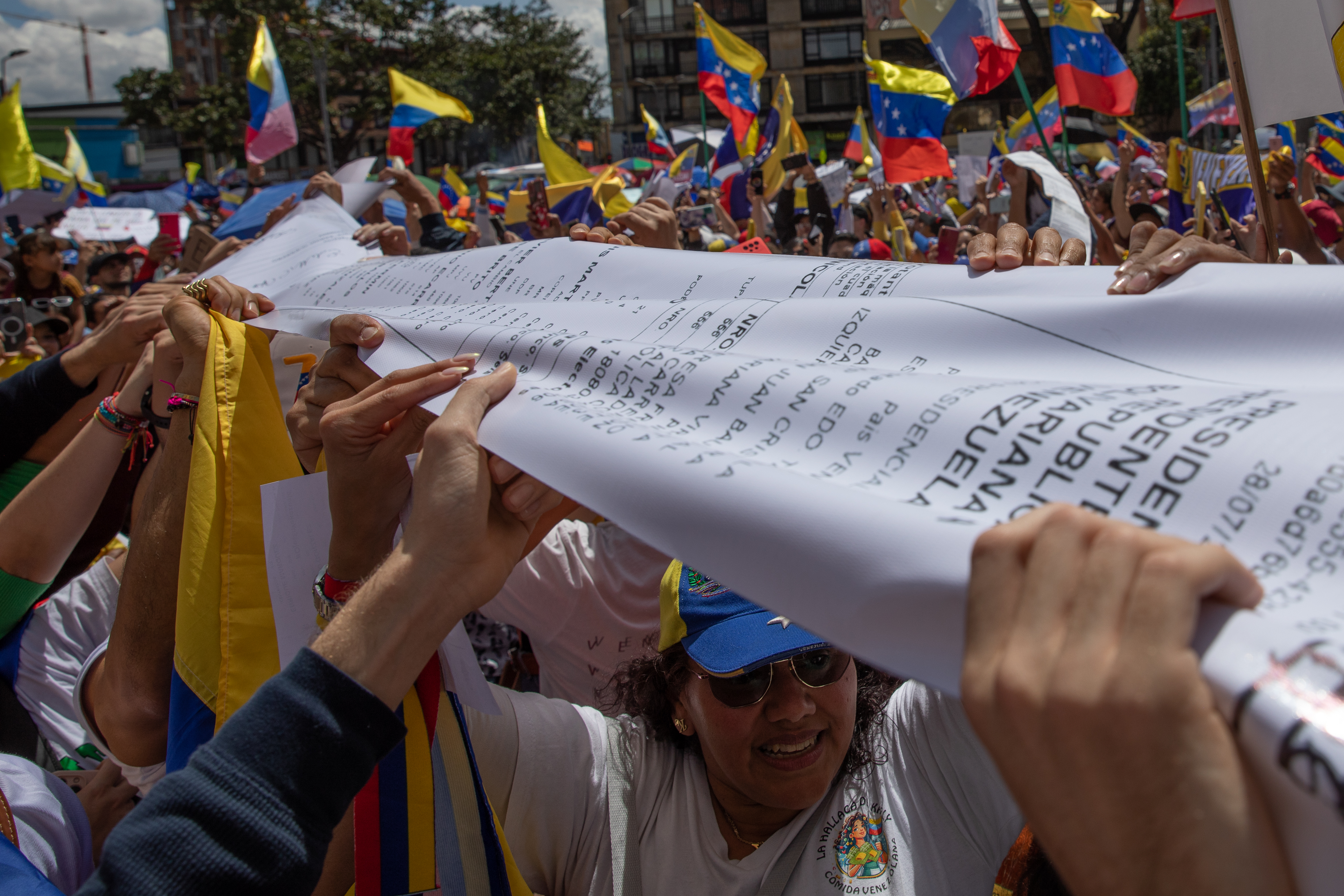 Venezuelan protesters in Bogota stretch a giant print-out of the voter tallies across the crowd, while others wave Venezuelan flags.