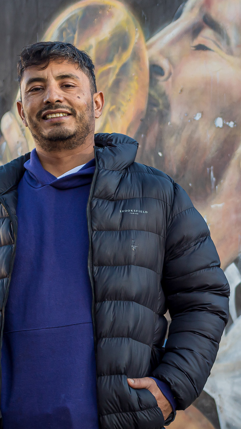 Waldemar Cubilla stands in front of a mural of Lionell Messi kissing the World Cup trophy