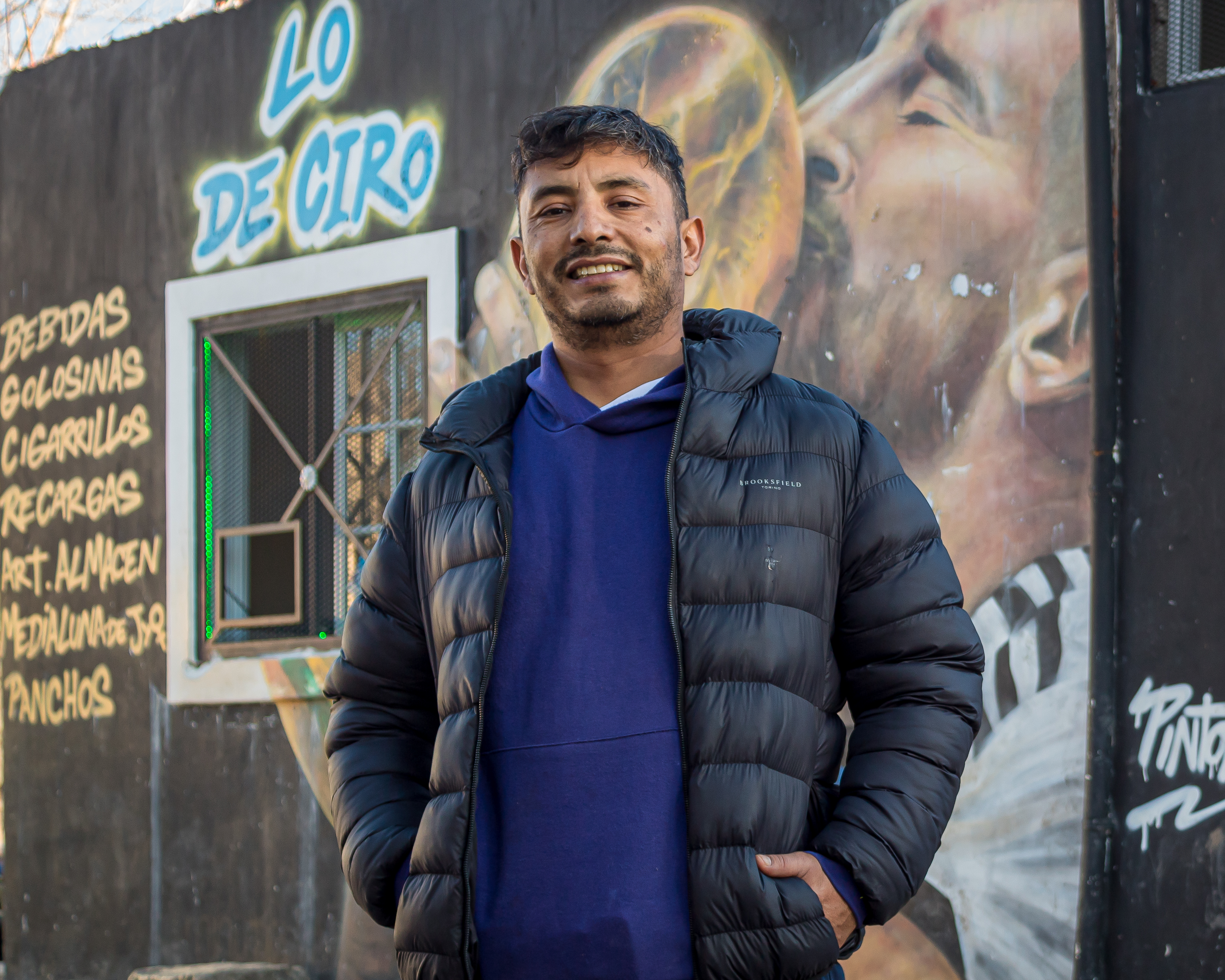 Waldemar Cubilla stands in front of a mural of Lionell Messi kissing the World Cup trophy