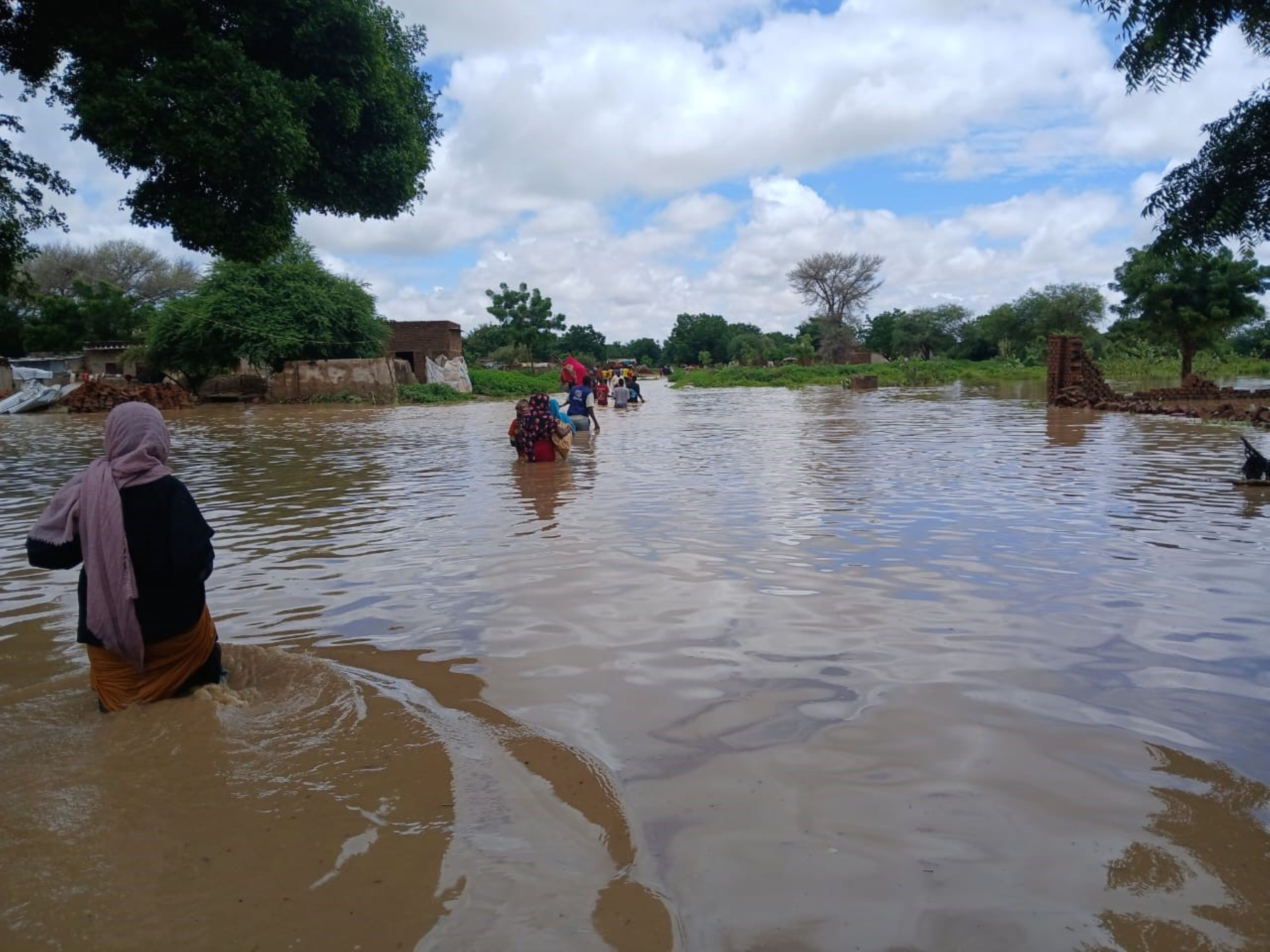 a photo of flooded plains with a veiled woman trying to wade through the water