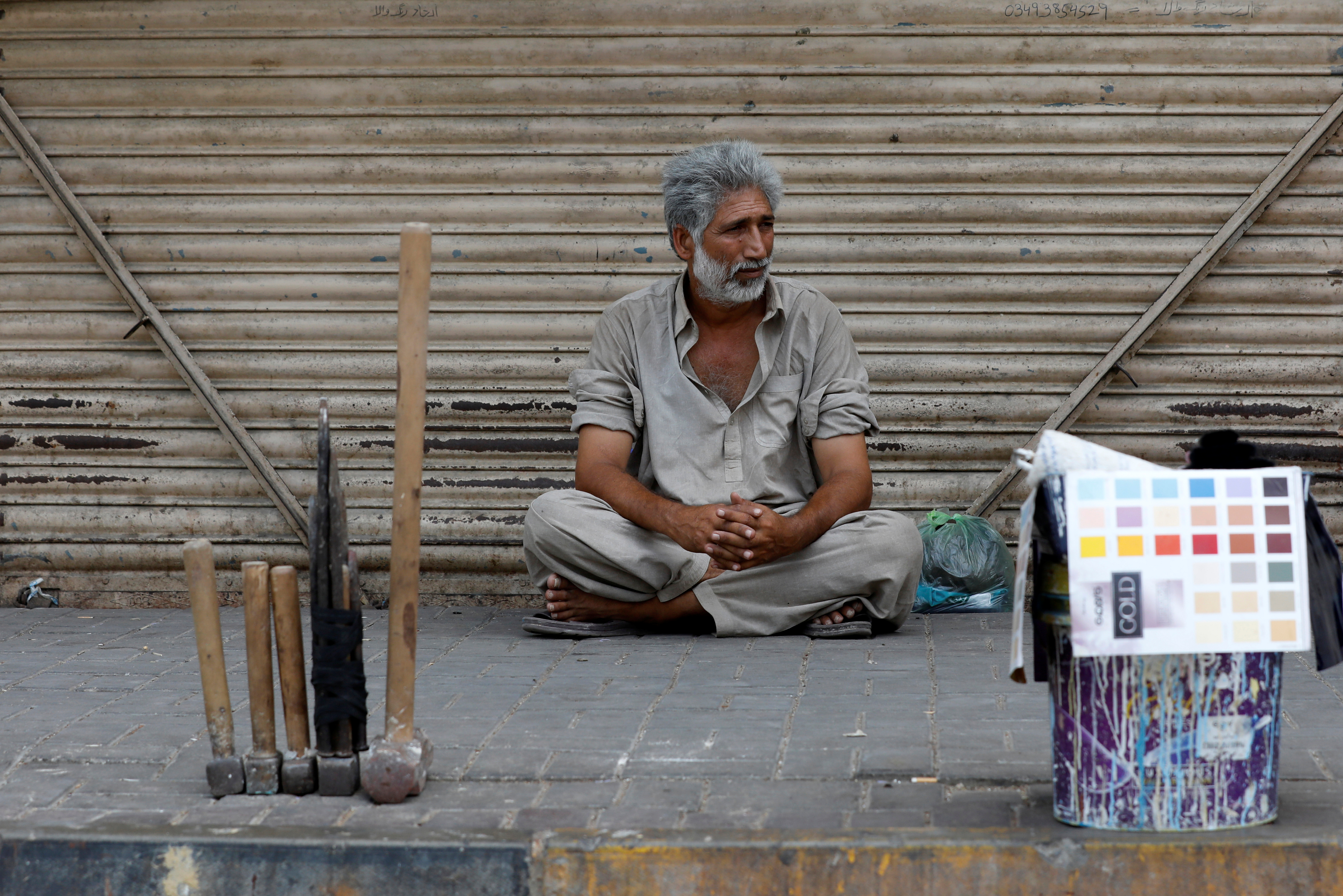 Mohammad Fakhir, 49, father of three and a laborer, sits with his tools as he waits for work along a side walk in Karachi, Pakistan May 21, 2019. Fakhir earns Pakistani Rupees 1500/(~US$9.9) when he gets a day job. REUTERS/Akhtar Soomro