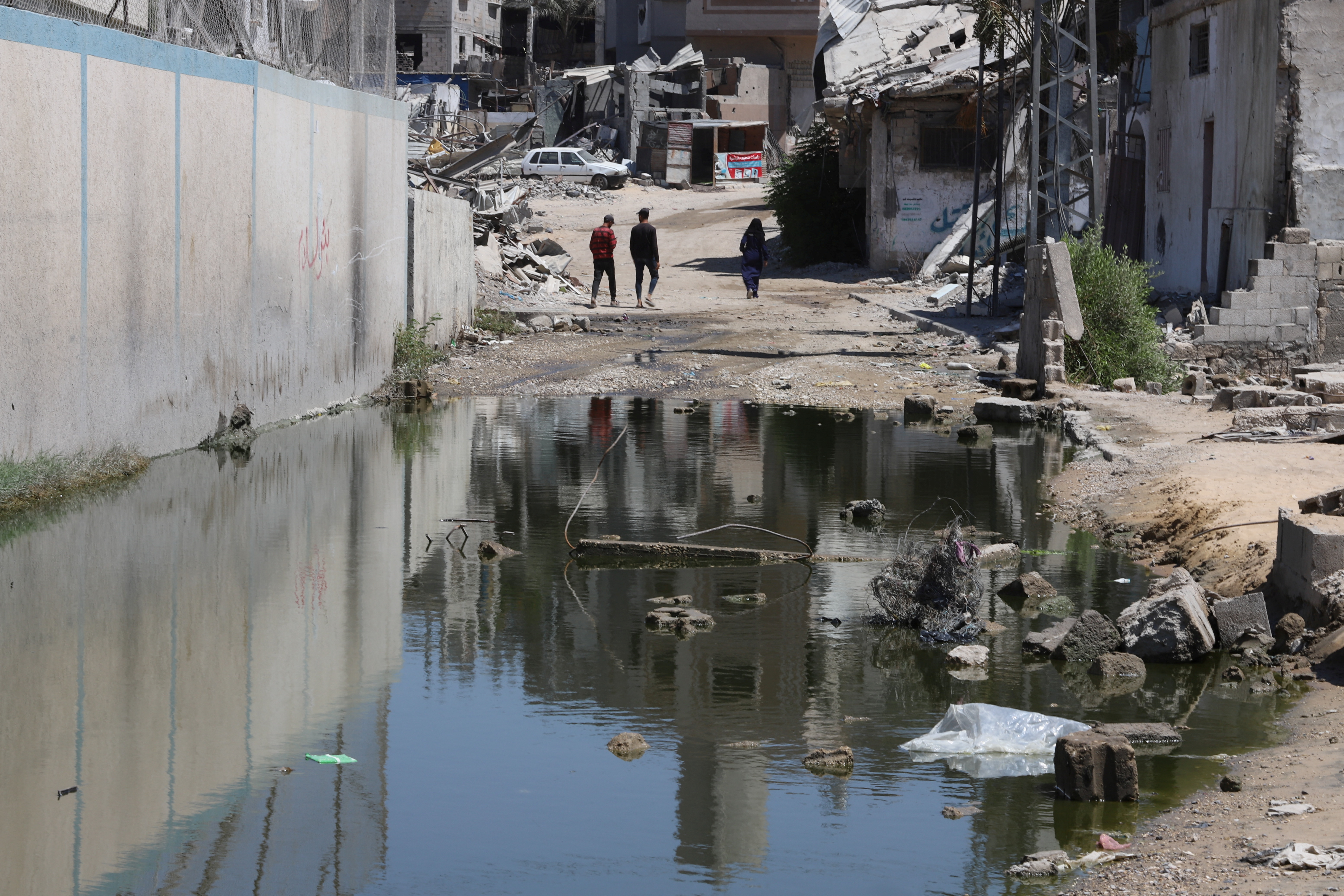 Palestinians walk near a puddle of waste water, amid Israel-Hamas conflict, in Khan Younis in the southern Gaza Strip July 30, 2024. REUTERS/Hatem Khaled