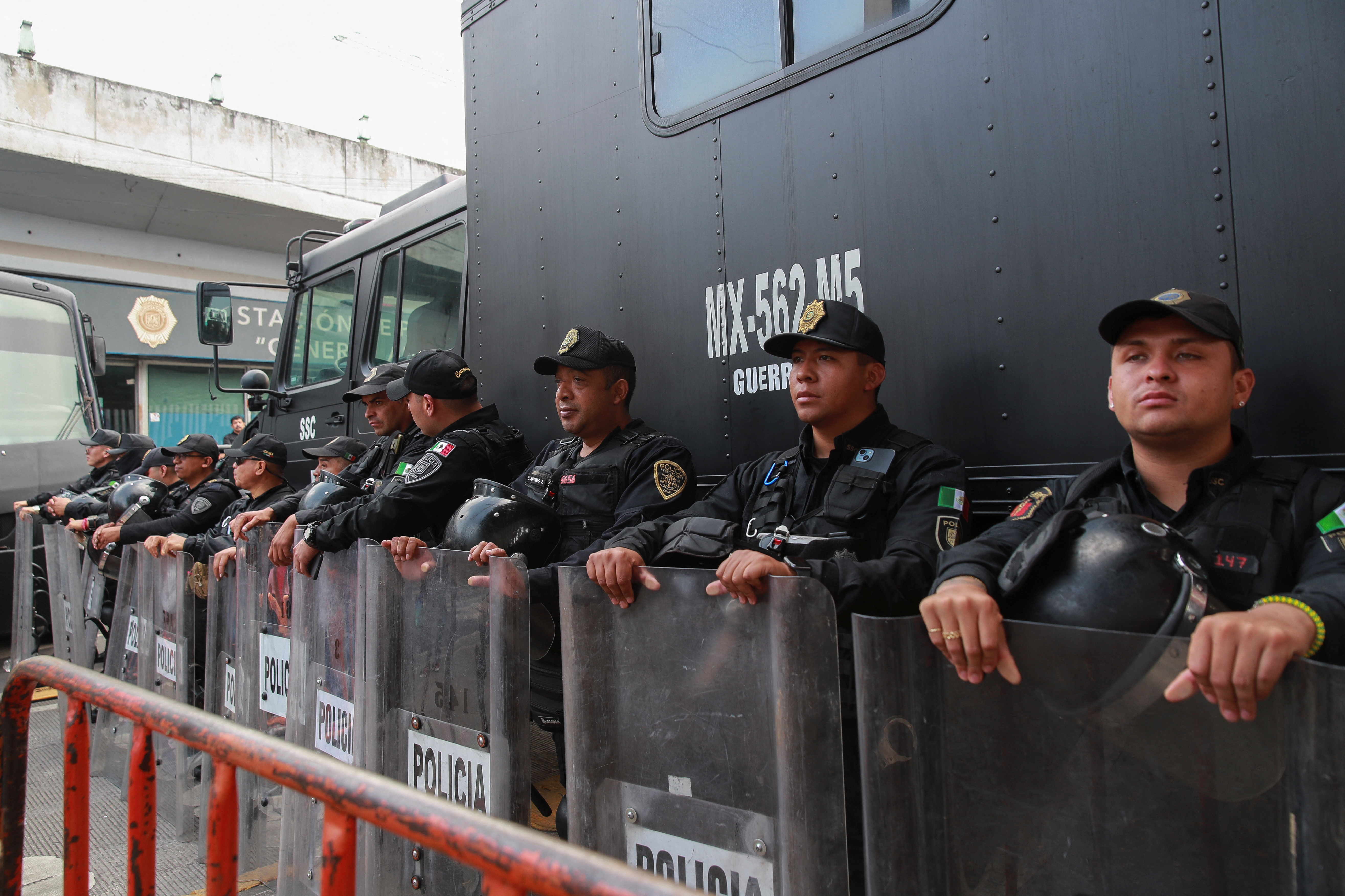 Police officers stand guard in Mexico City, holding up clear plastic shields.