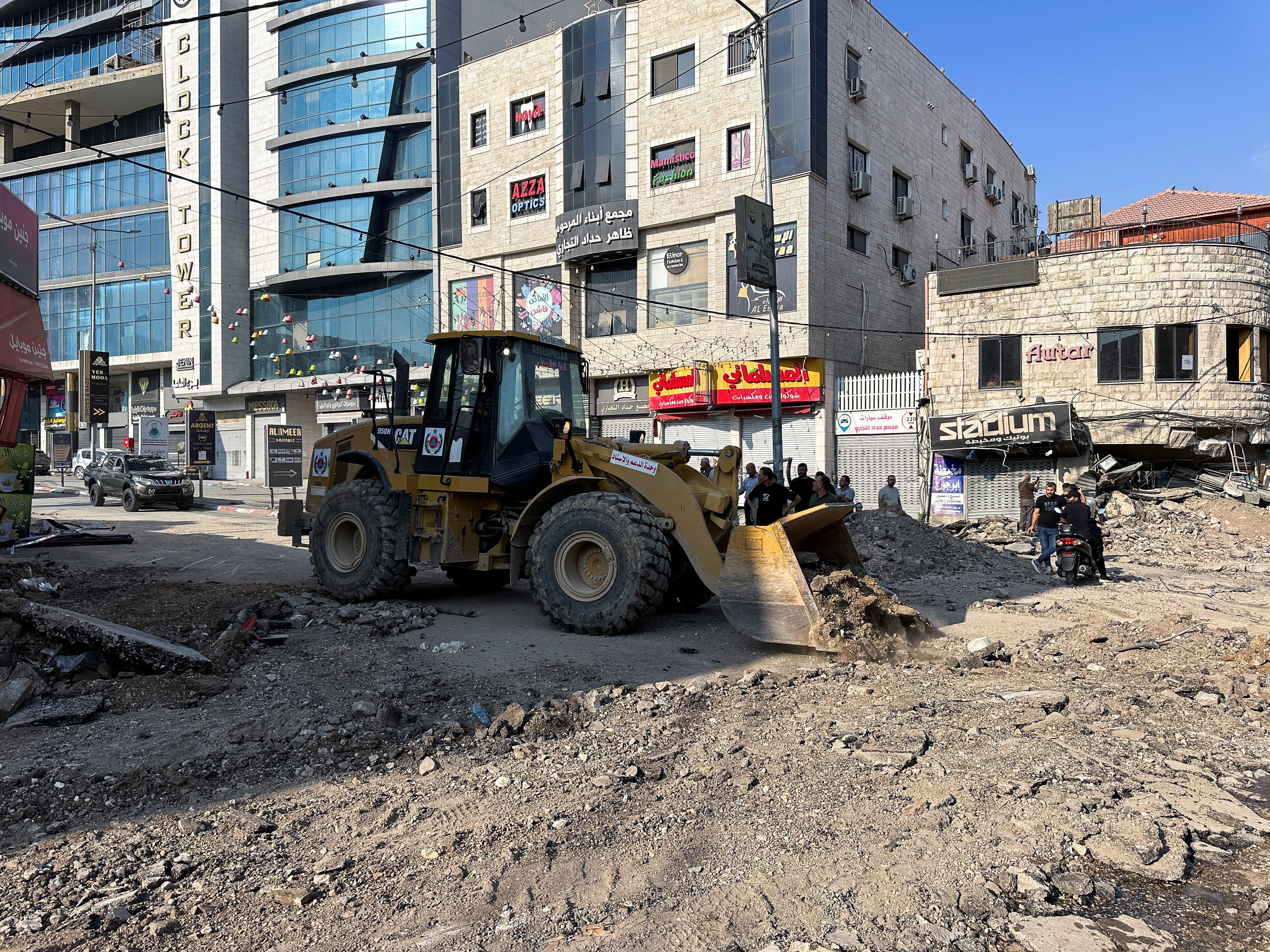 Palestinians assess damage in the street following an Israeli military operation in Jenin