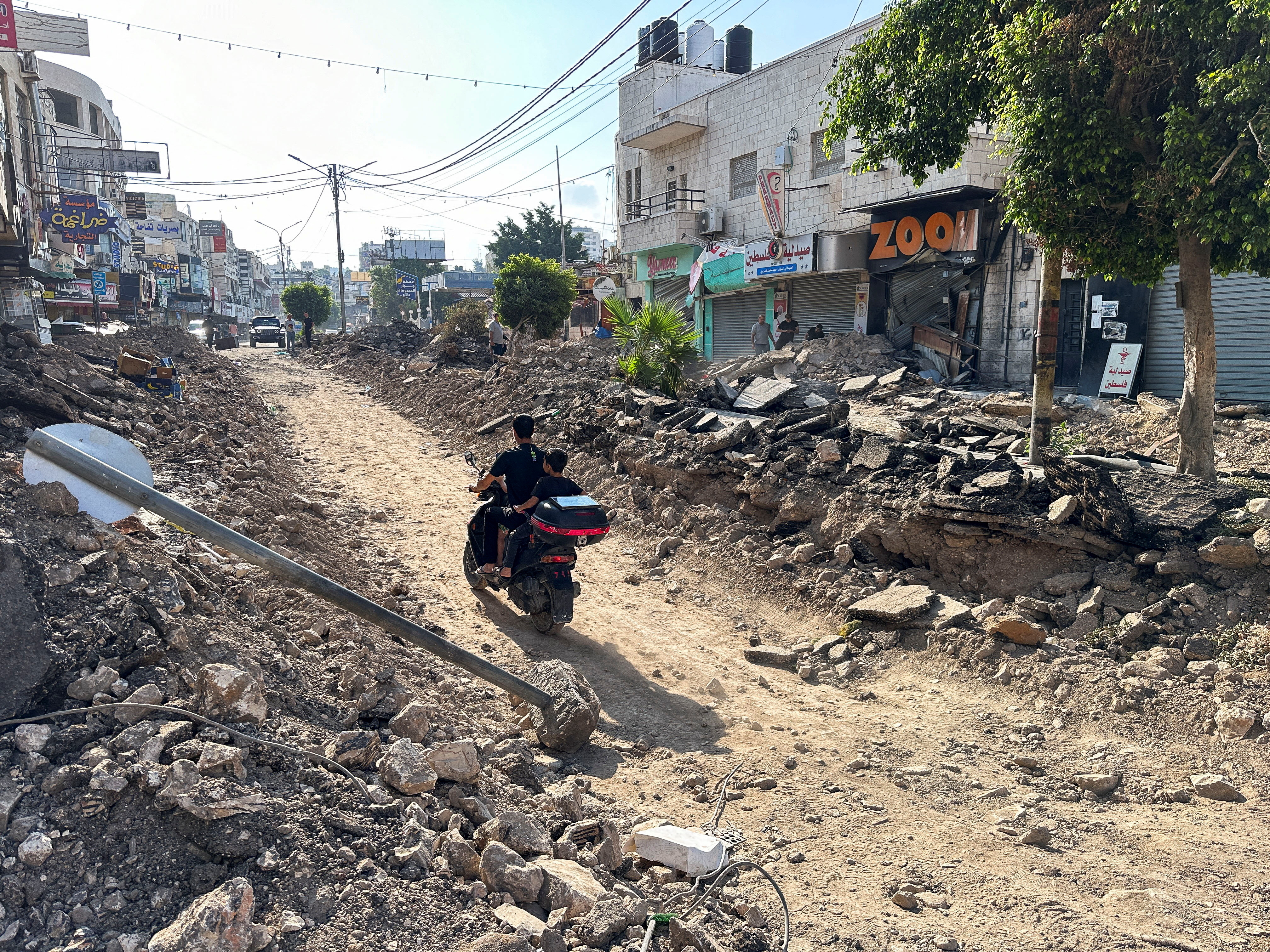 Palestinians assess damage in the street following an Israeli military operation in Jenin