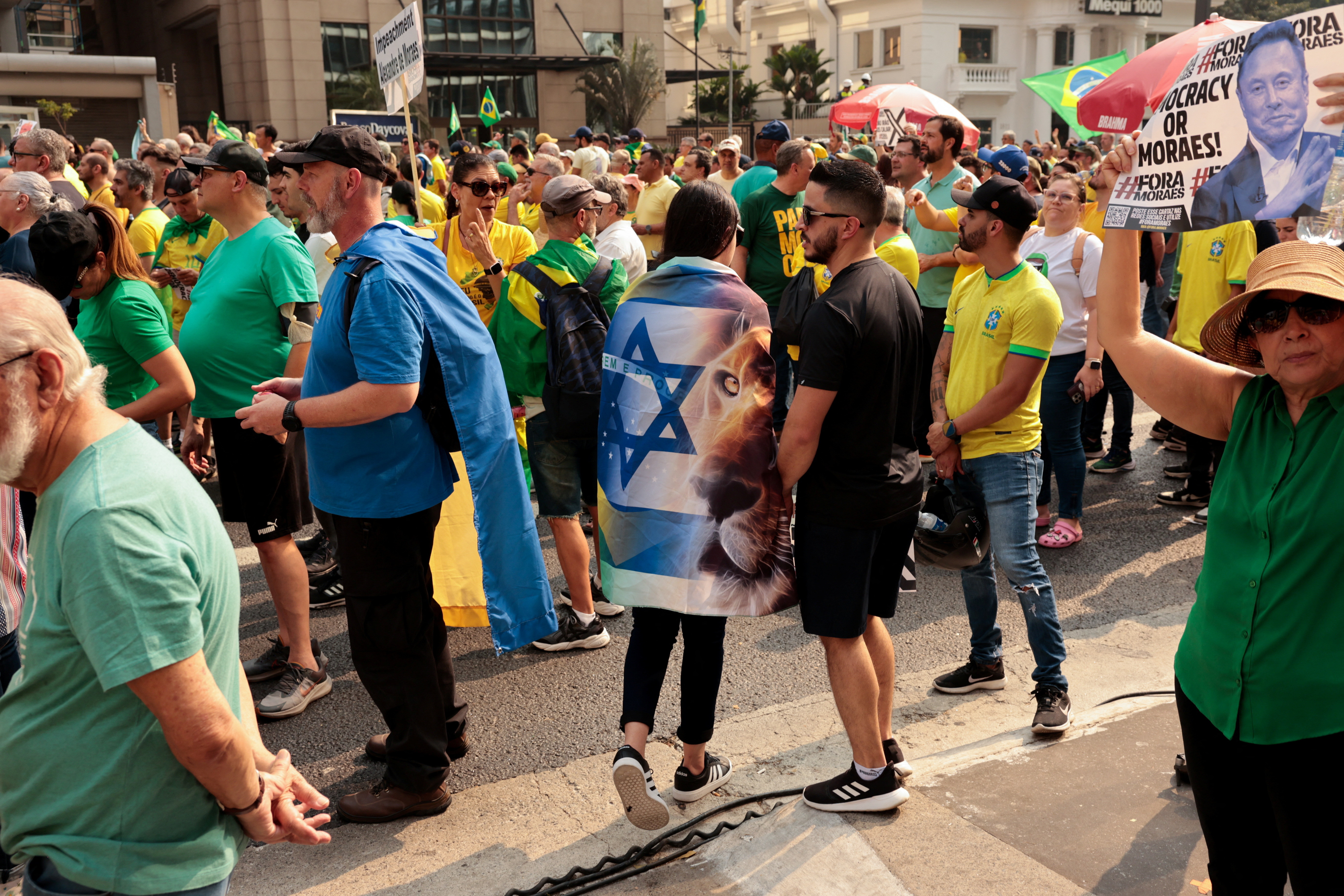 A protester in Brazil wraps themselves in an Israeli flag.