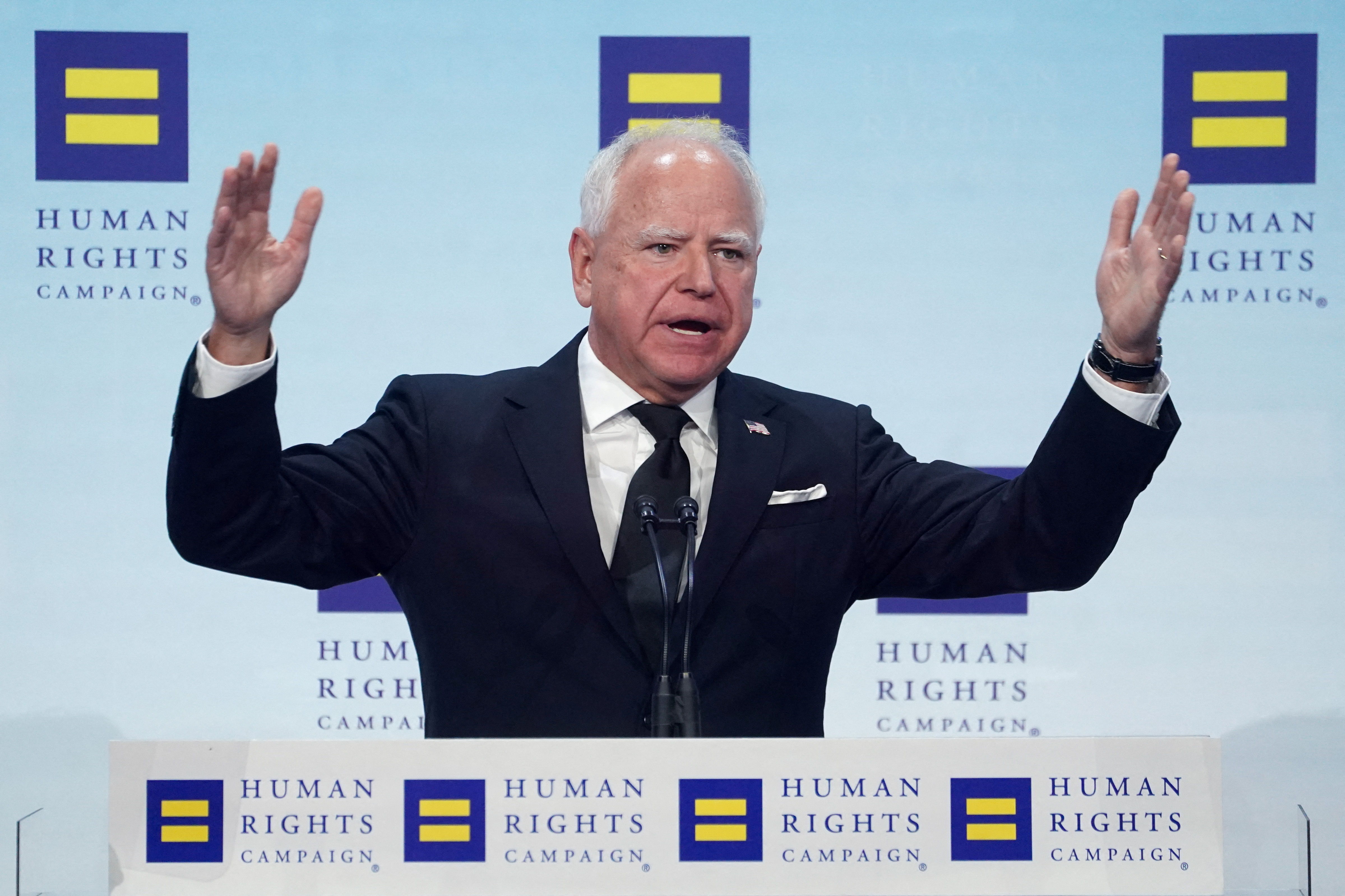 Tim Walz raises hands while on stage