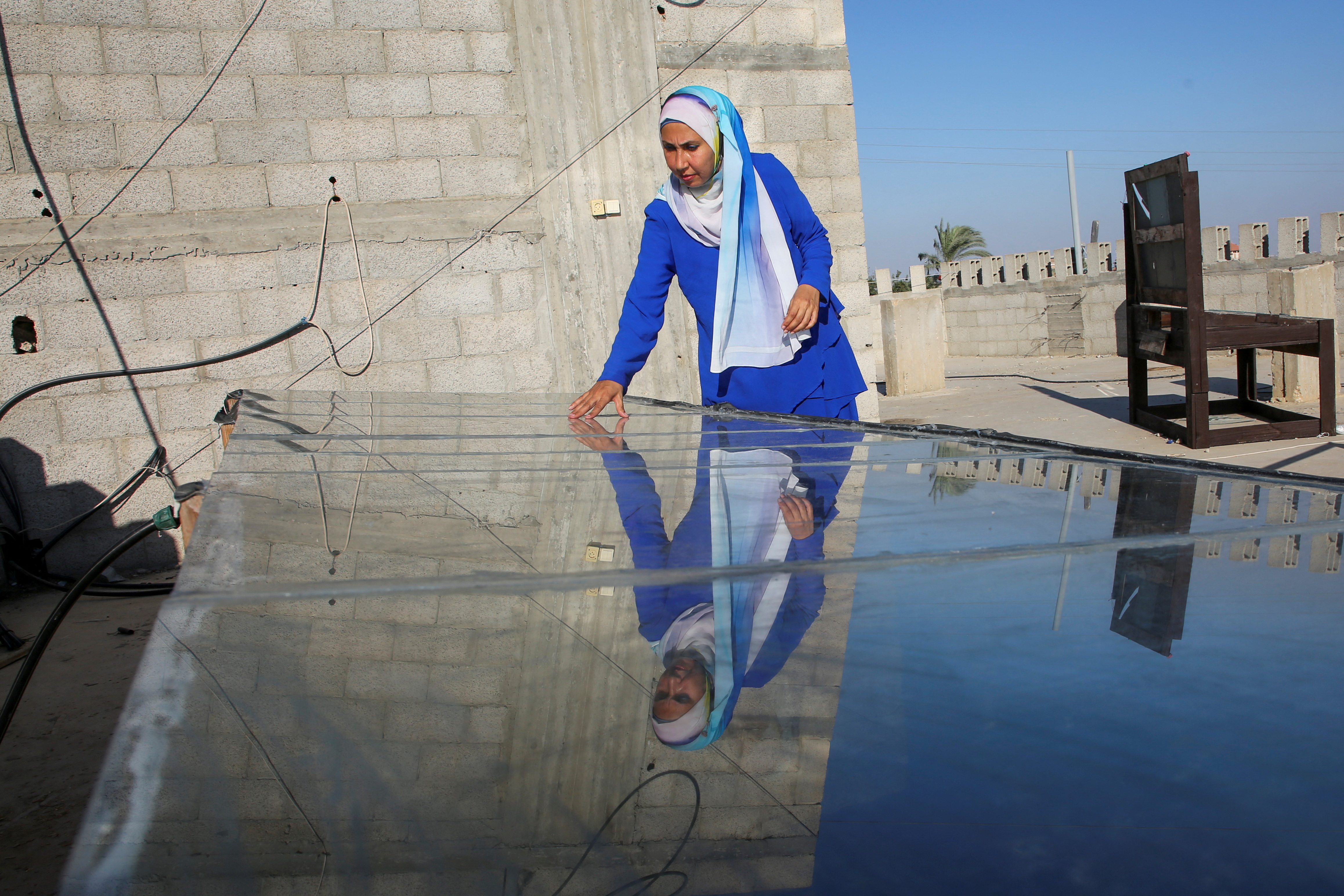 Inas Al-Ghoul, a Palestinian engineer, checks a solar water desalination system she built in response to a water crisis