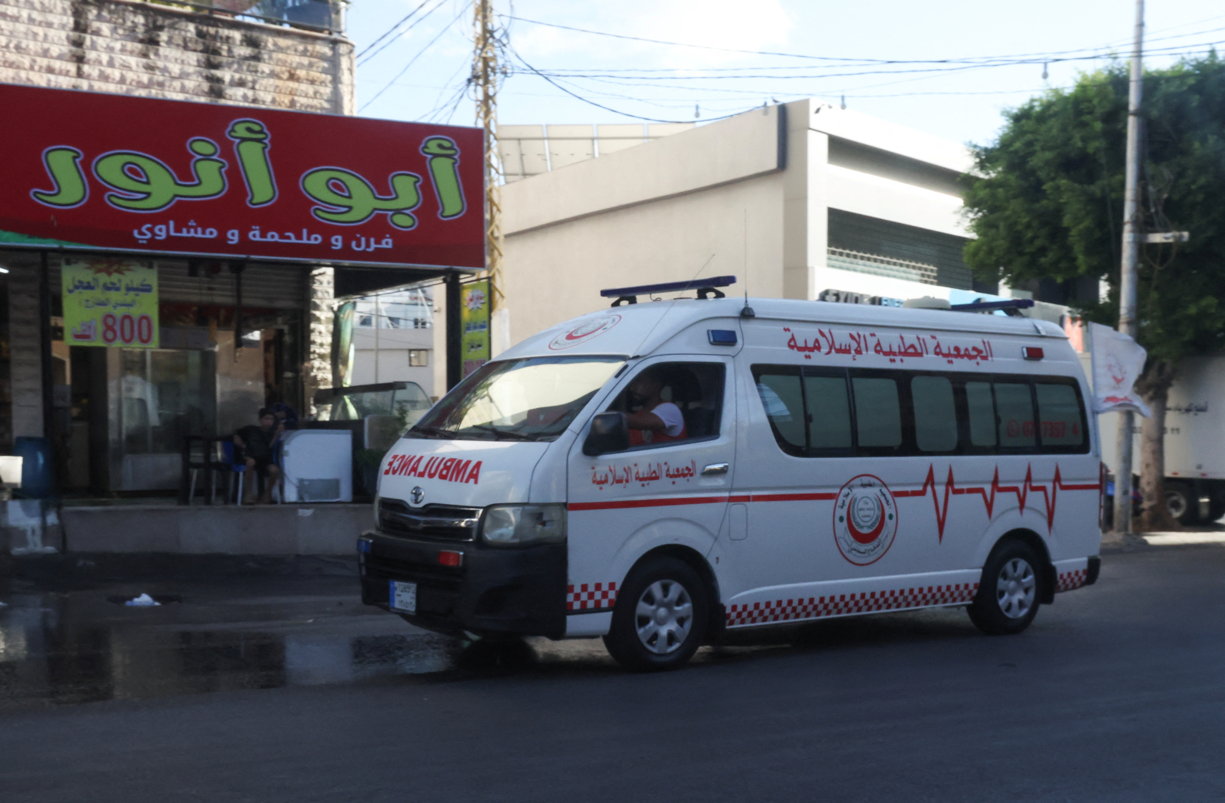 An ambulance vehicle drives as hundreds of members of Hezbollah
