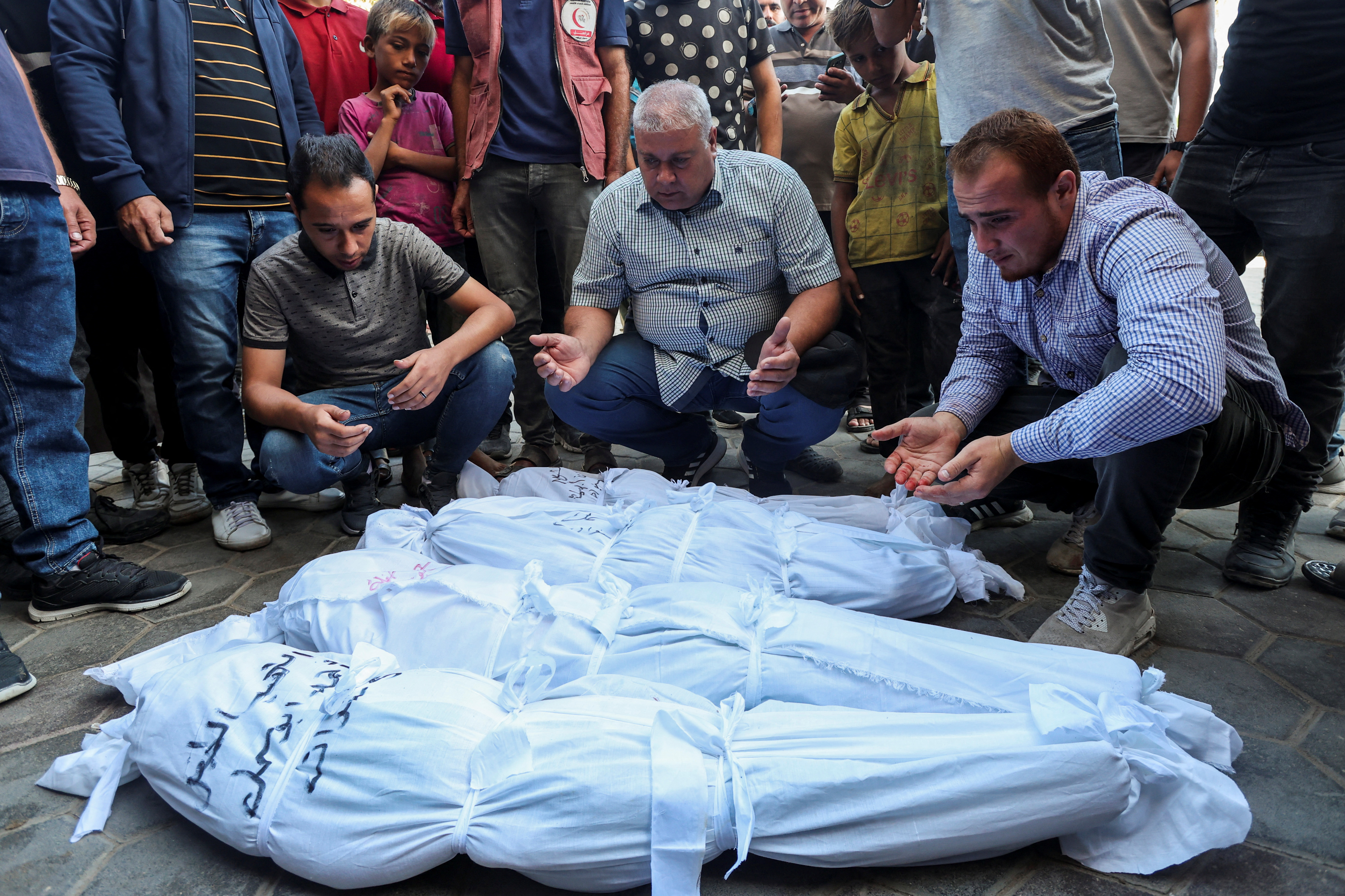 Mourners pray next to the bodies of Palestinians killed in Israeli strikes