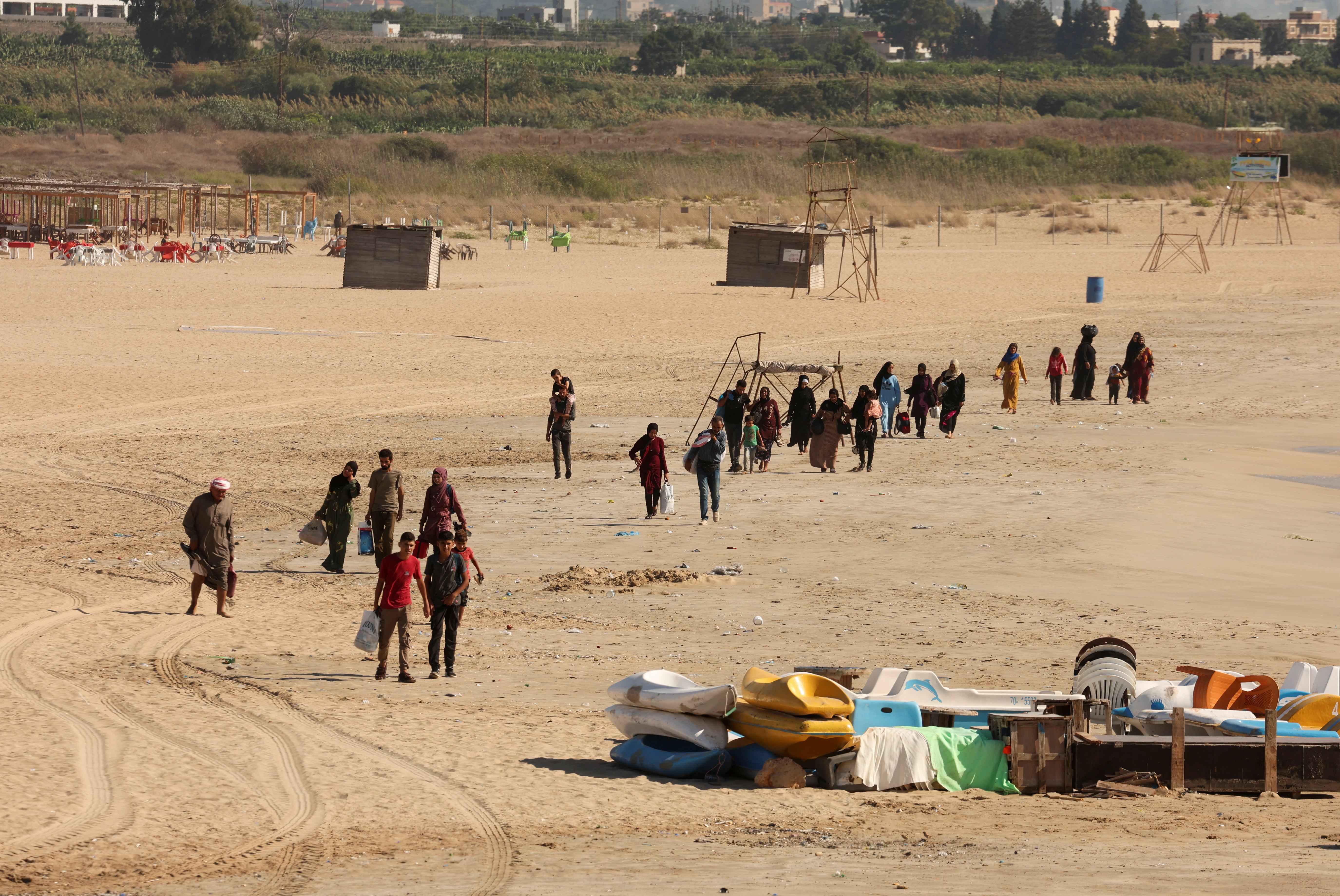 People carry belongings at a beach as they flee, amid ongoing cross-border hostilities between Hezbollah and Israeli forces