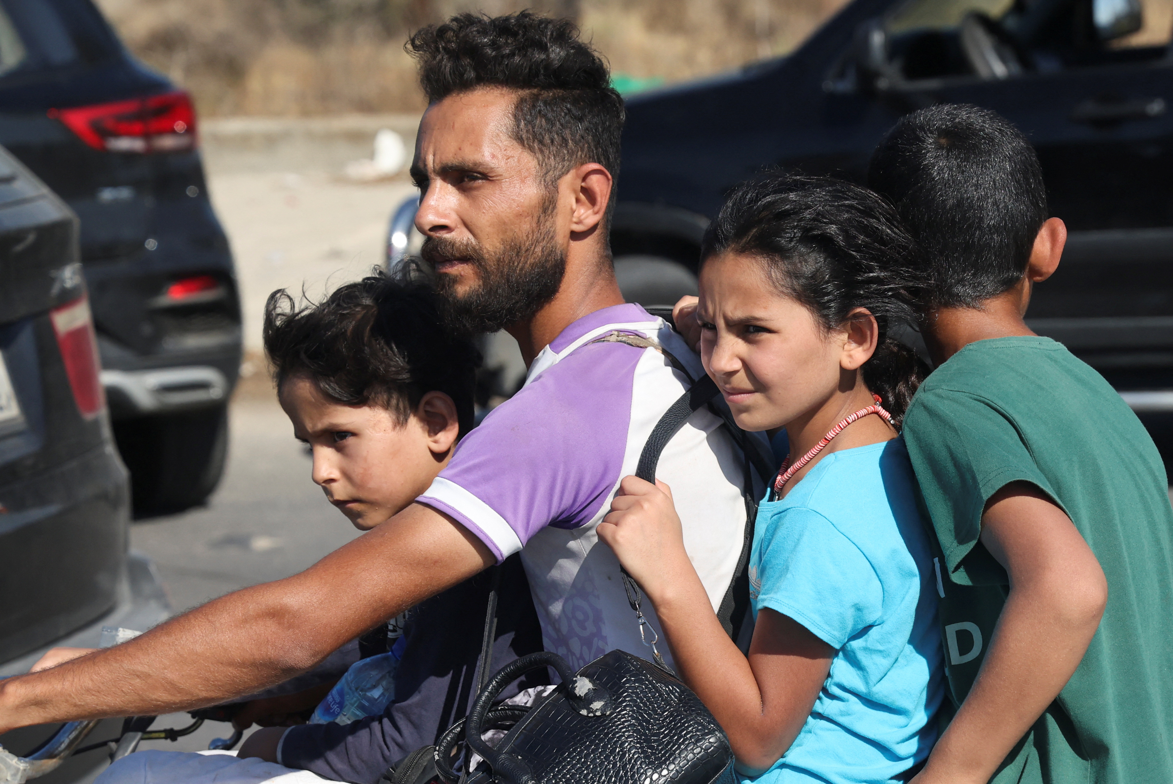A man and children ride a motorcycle as people in heavy traffic drive north from Lebanon's southern coastal city Sidon as some of them flee Israeli bombardment