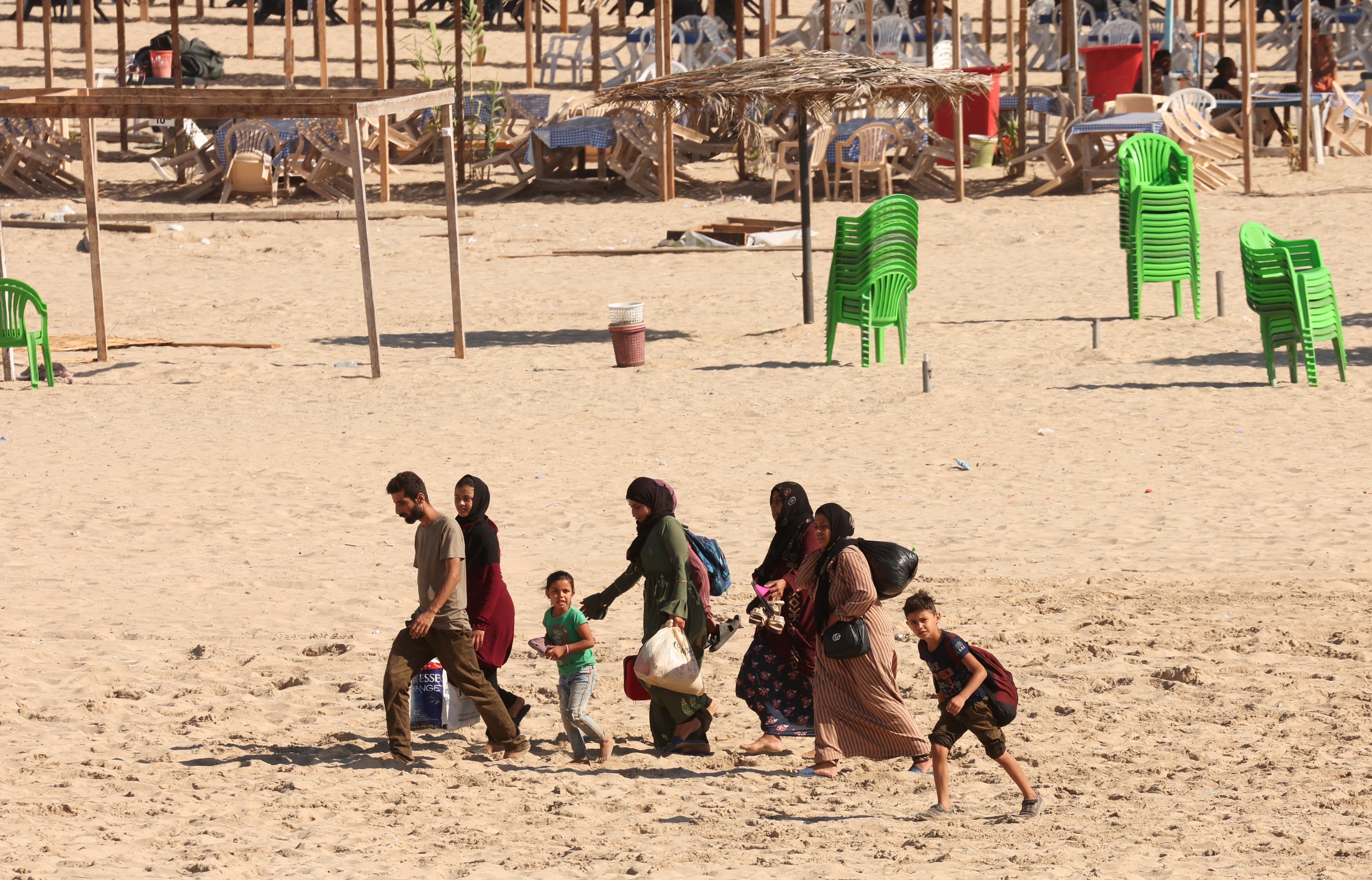 People carry belongings at a beach as they flee, amid ongoing cross-border hostilities between Hezbollah and Israeli forces