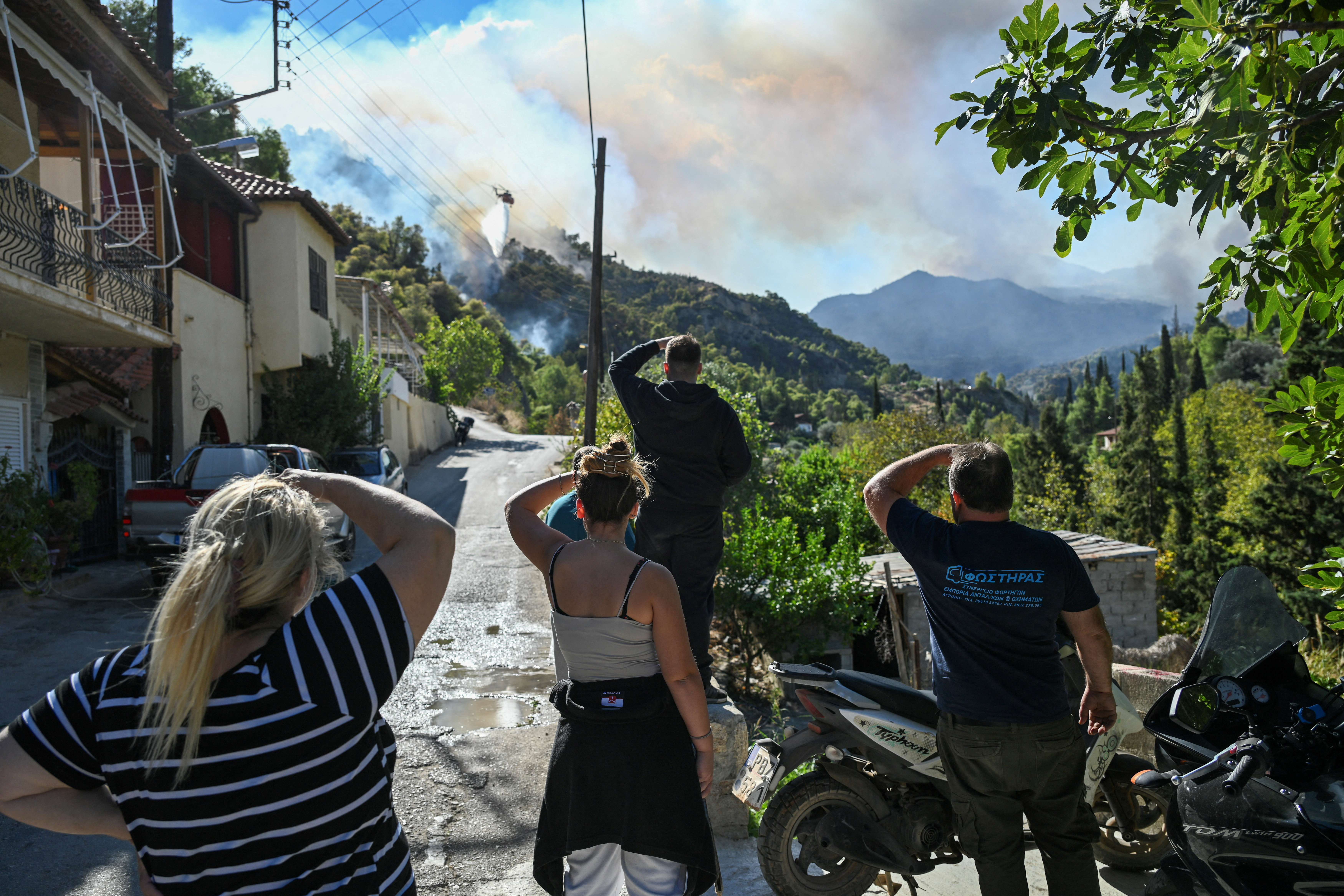 Locals watch a wildfire burning near the village of Helidori, near Corinth, Greece, September 30