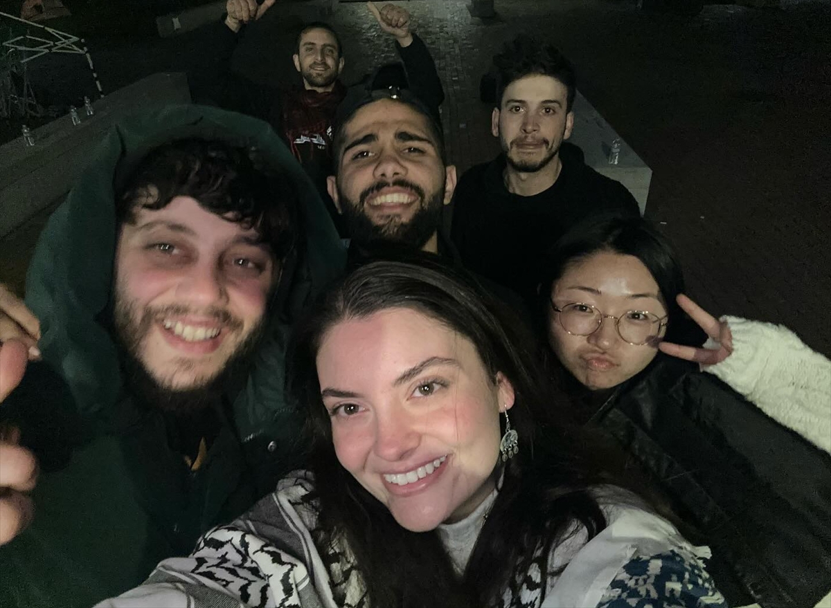 a young woman wearing a keffiyeh poses smiling with friends
