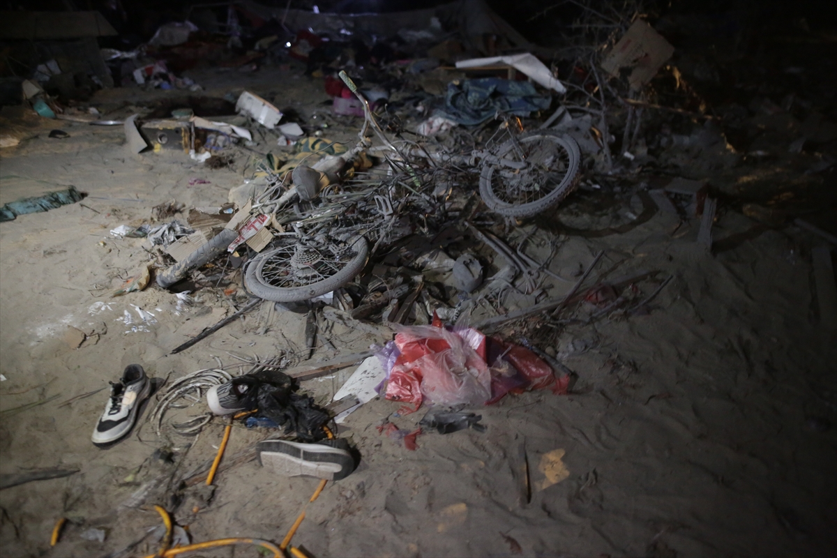 people look through a destroyed tent camp at night