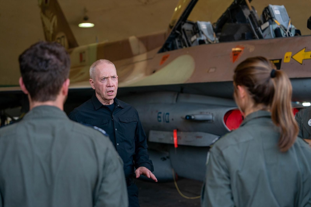 a man wearing black speaks in front of a military plane