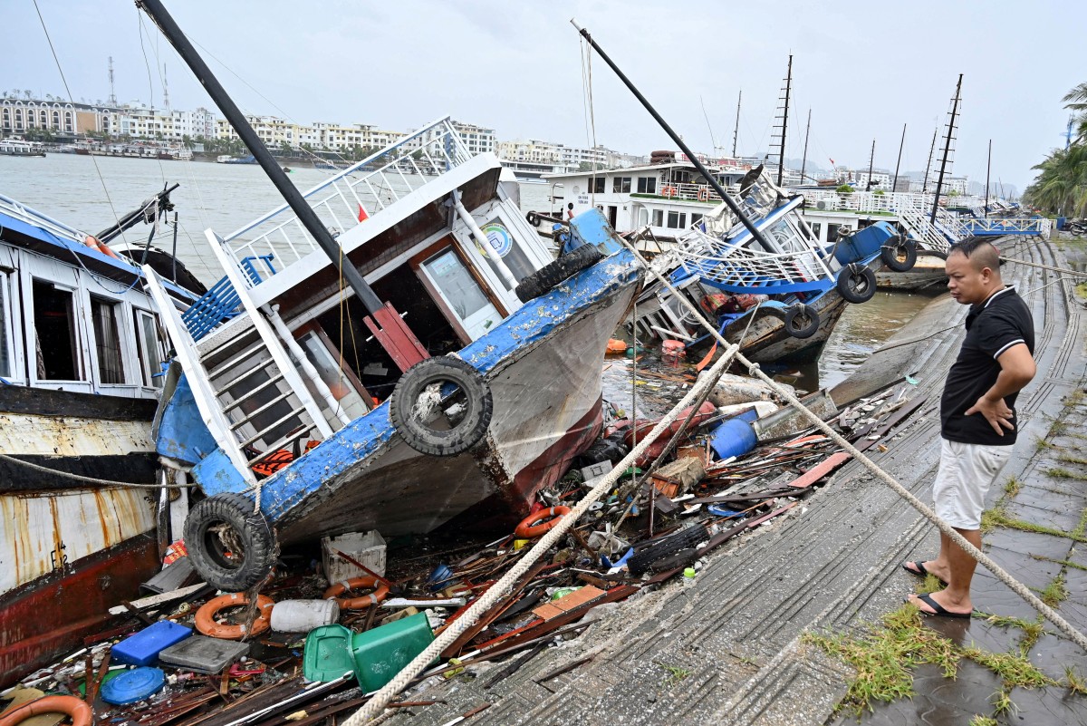 A man checks boats damaged after Super Typhoon Yagi hit Ha Long bay, in Quang Ninh province