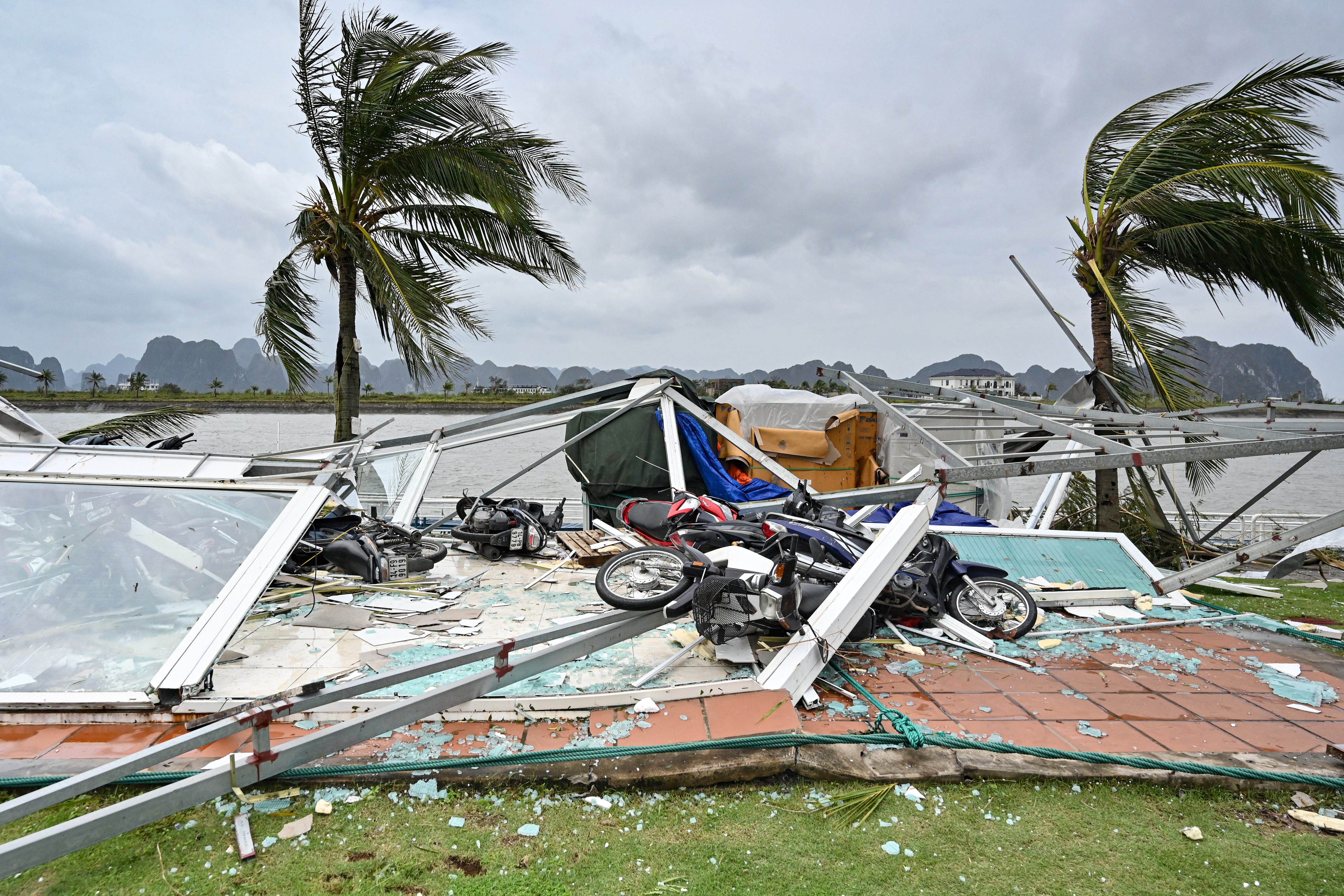 TOPSHOT - This picture shows swept motorbikes with the debris of destroyed waiting lounges on the shore after Super Typhoon Yagi hit Ha Long bay, in Quang Ninh province, on September 8, 2024. Super Typhoon Yagi uproots thousands of trees, sweeps ships and boats out to sea and rips roofs off houses in northern Vietnam, after leaving a trail of destruction in southern China and the Philippines. (Photo by Nhac NGUYEN / AFP) Related conten