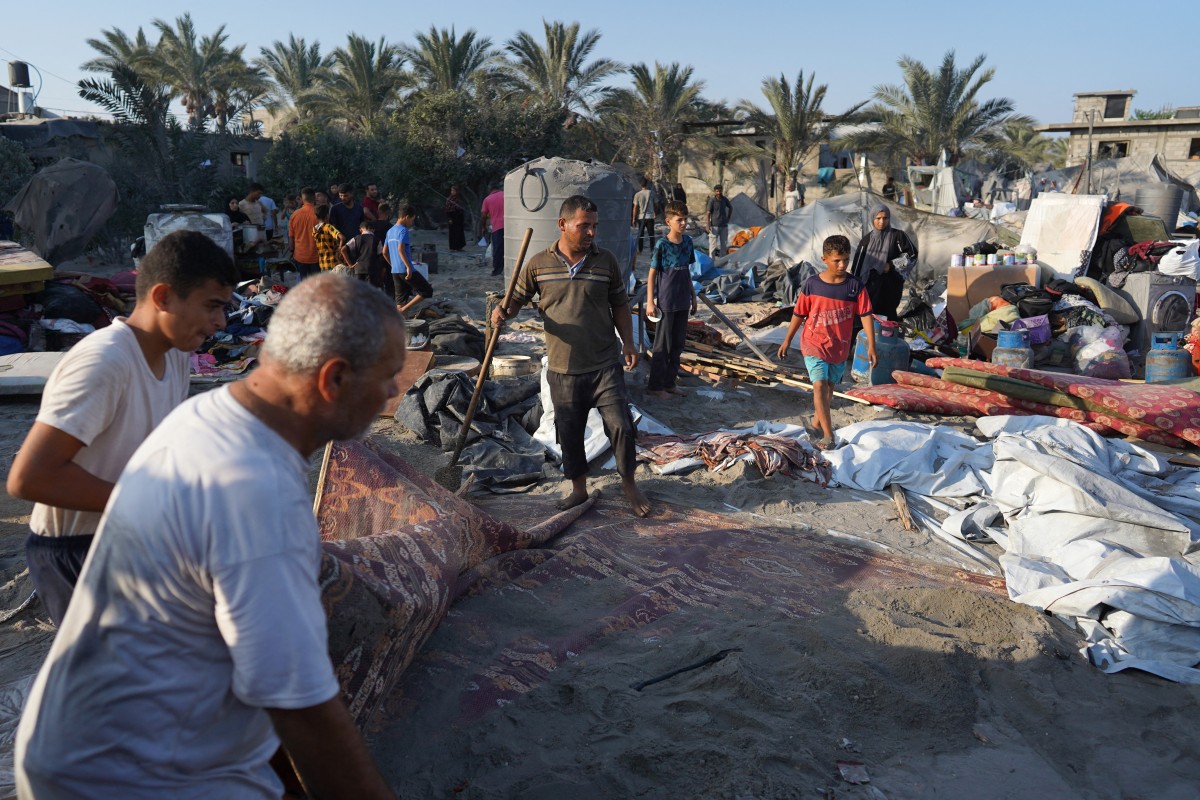 Palestinians gather their belongings at the site of Israeli strikes on a makeshift displacement camp in Mawasi