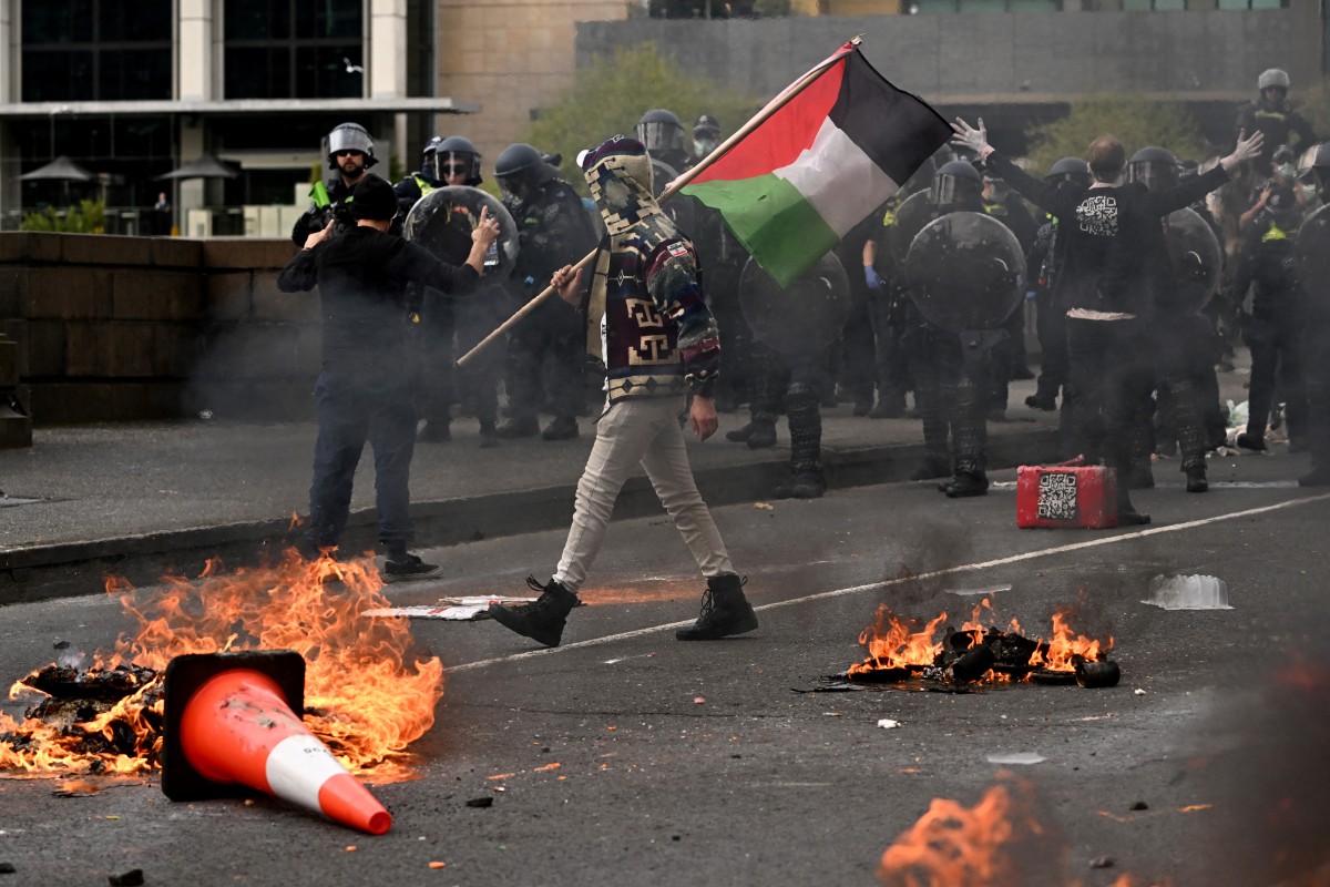 A man waves a Palestinian flag as protesters confront police outside the Land Forces 2024 arms fair in Melbourne