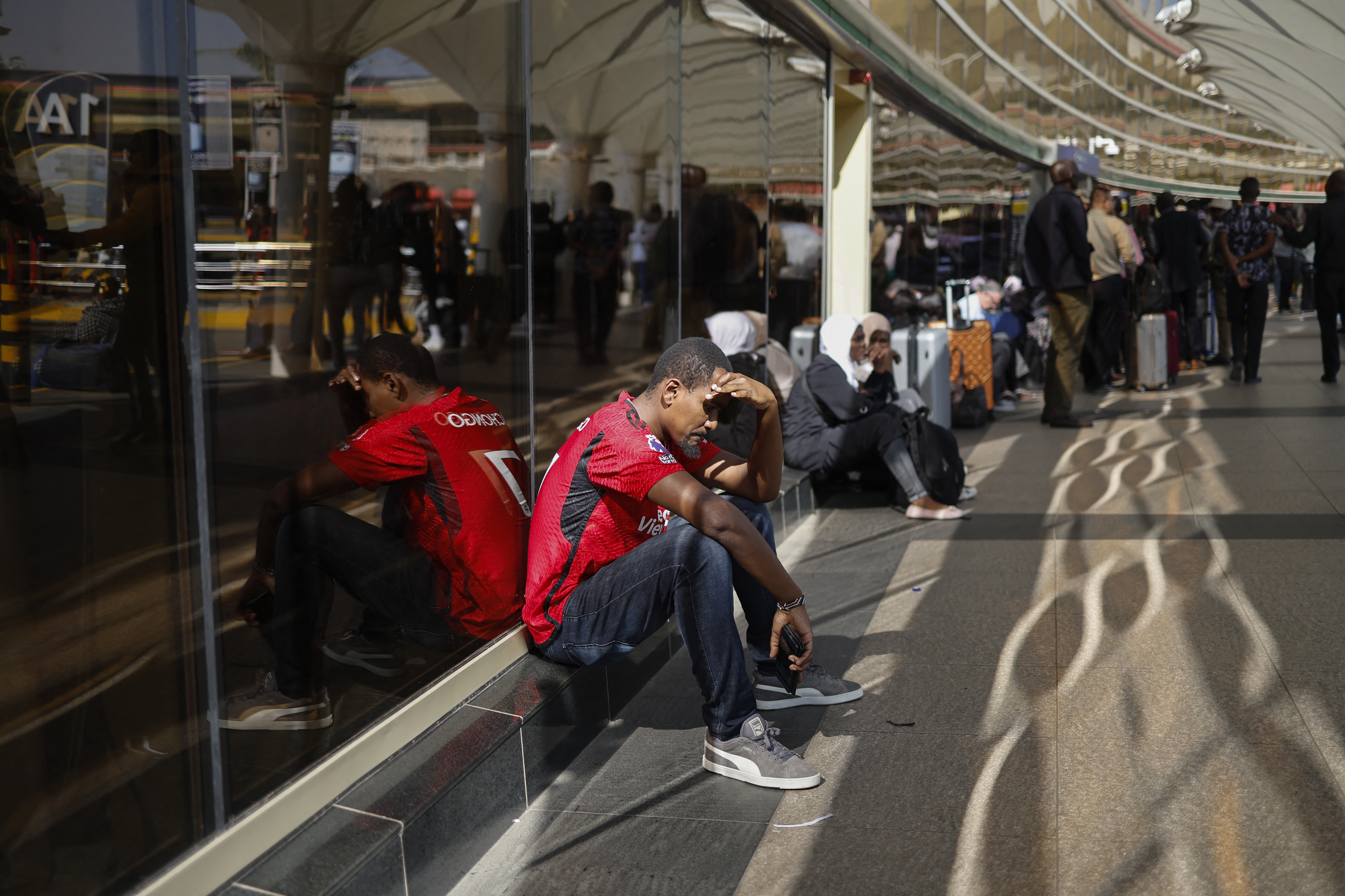 Passengers wait at a closed door at the departures of the Jomo Kenyatta International Airport (JKIA) in Nairobi on September 11, 2024 amid a strike by the Kenyan Aviation Workers Union. - There were chaotic scenes at Kenya's main airport overnight as staff went on strike early on September 11, 2024 over a planned takeover by an Indian company.