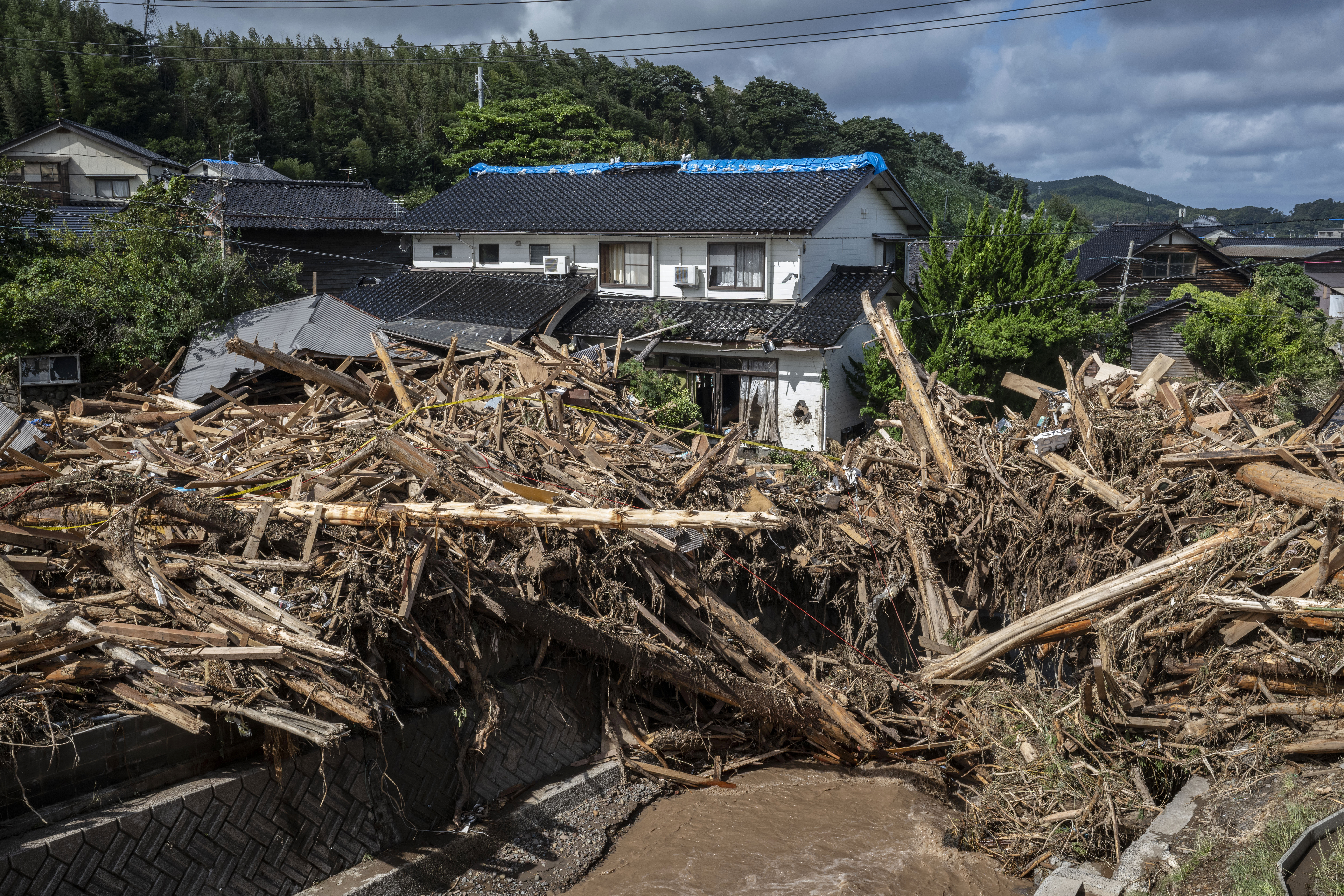 Debris piled up in Wajima by the floods. There is a house behind.