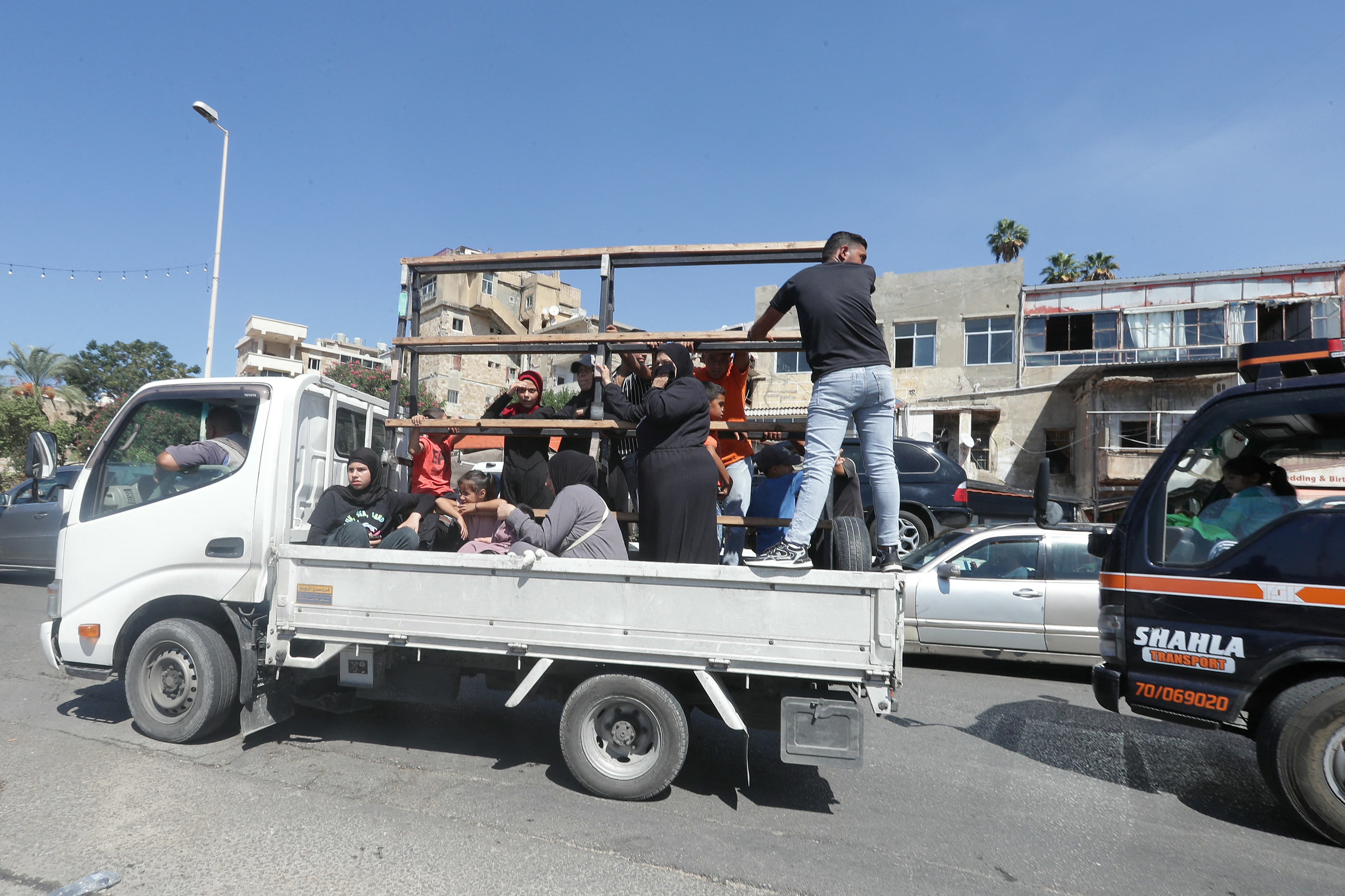 A Syrian family sit with their belongings in the back of a truck as they wait in a traffic jam in the southern Lebanese city of Sidon