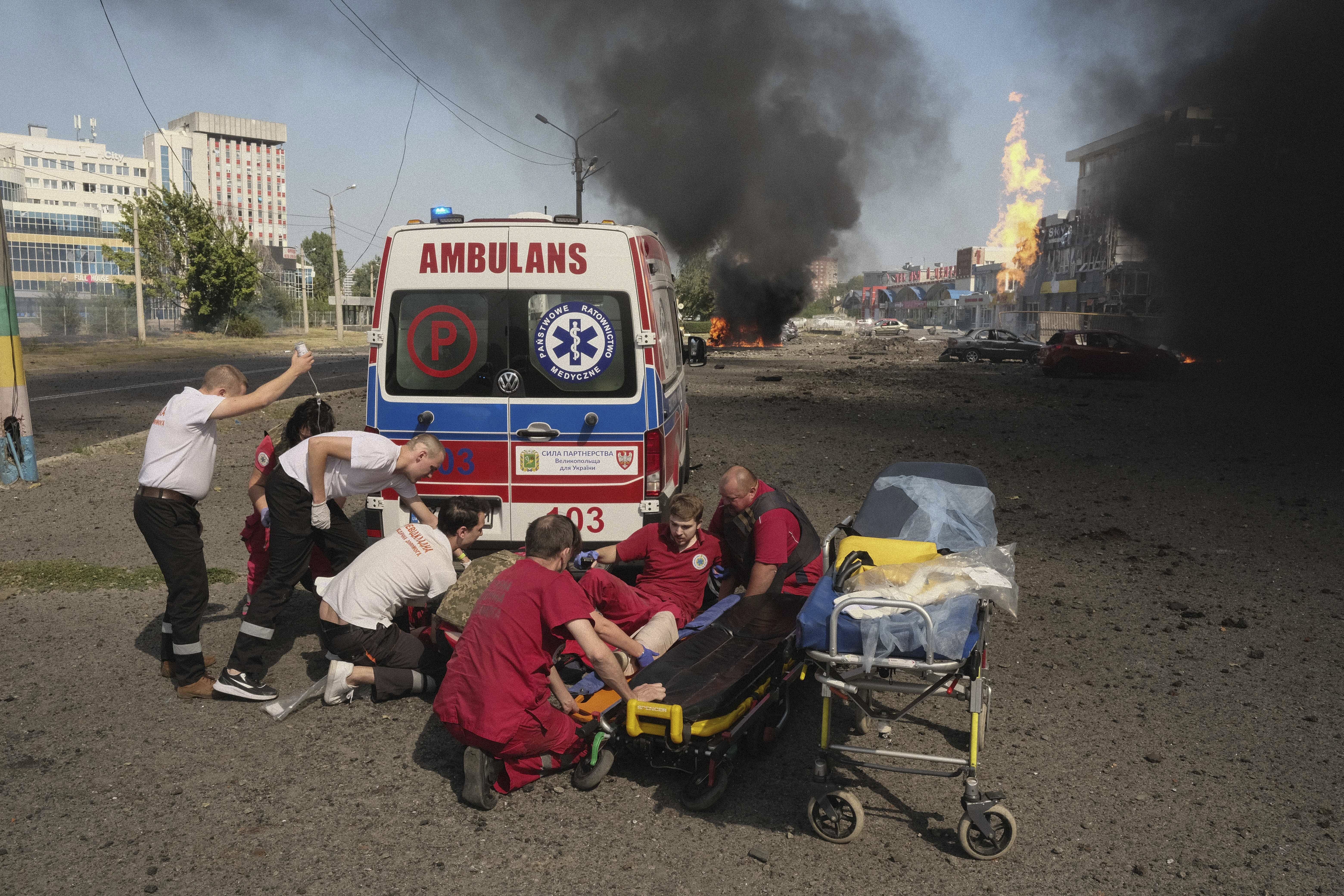 Paramedics give first aid to injured colleagues near an ambulance after twin Russian bombings in Kharkiv