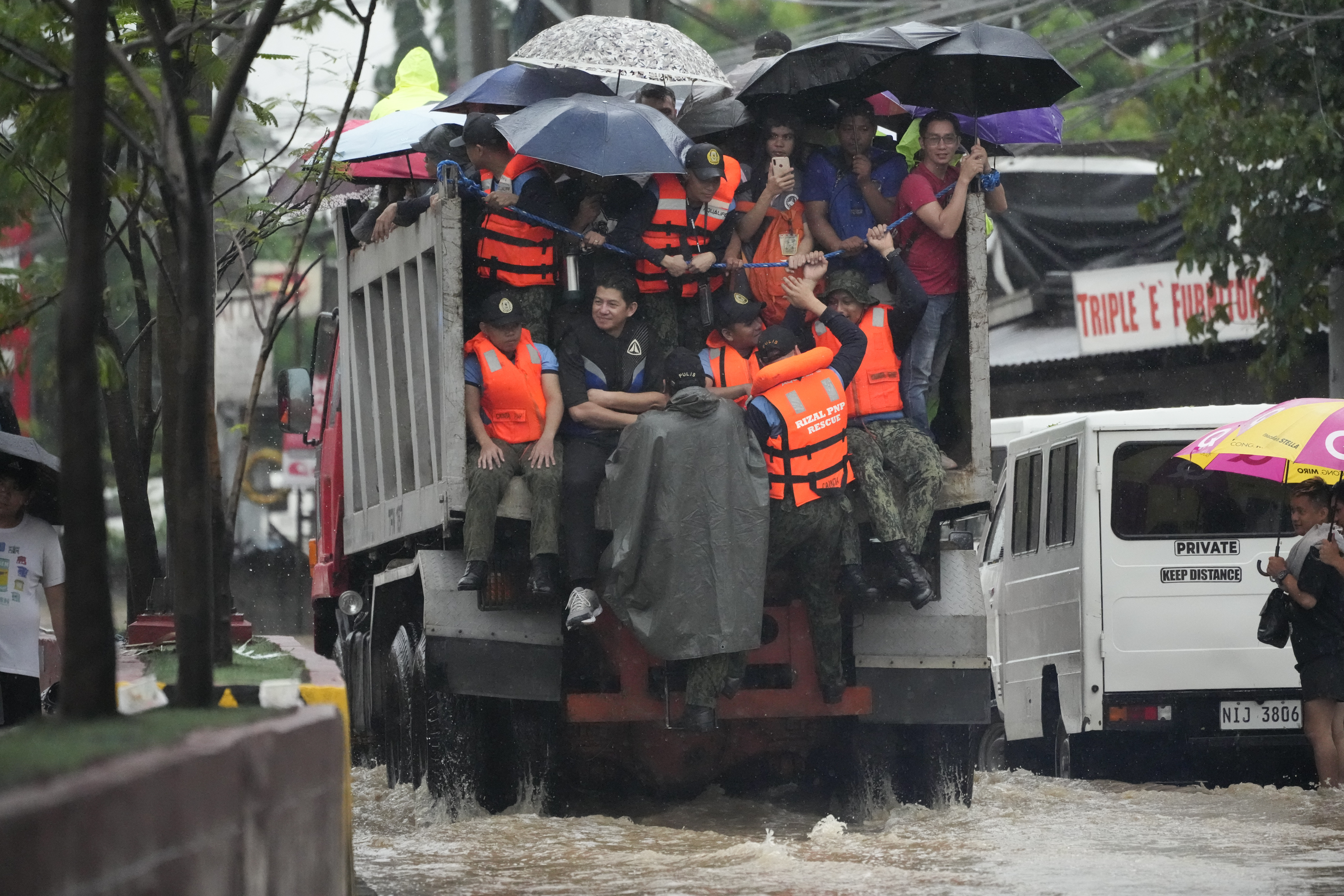 Rescuers and residents ride a truck as they cross a flooded street caused by heavy rains from Tropical Storm Yagi
