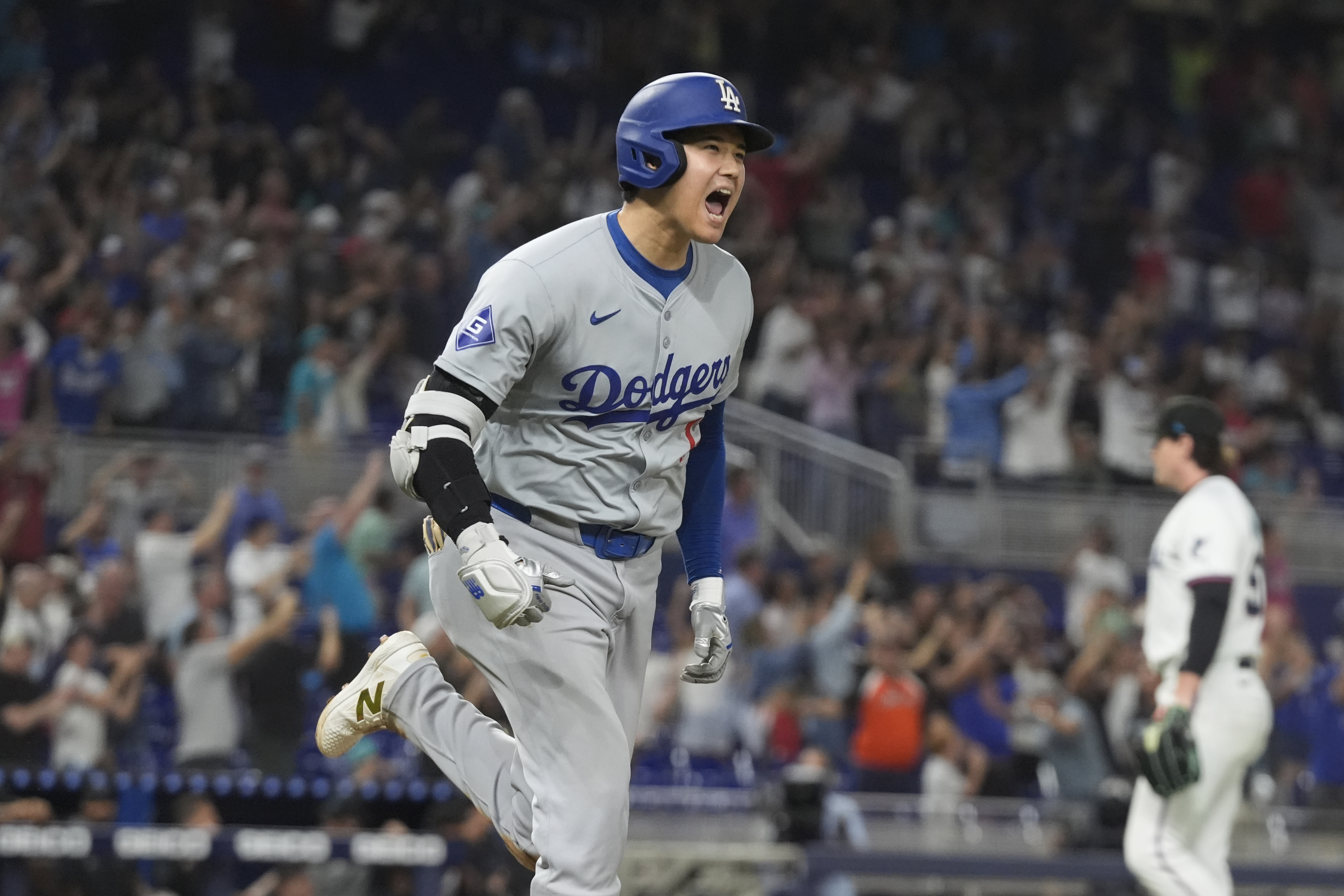 Shohei Ohtani running and cheering after hitting his 50th home run of the season. He's wearing te grey and blue kit of the Los Angeles Dodgers