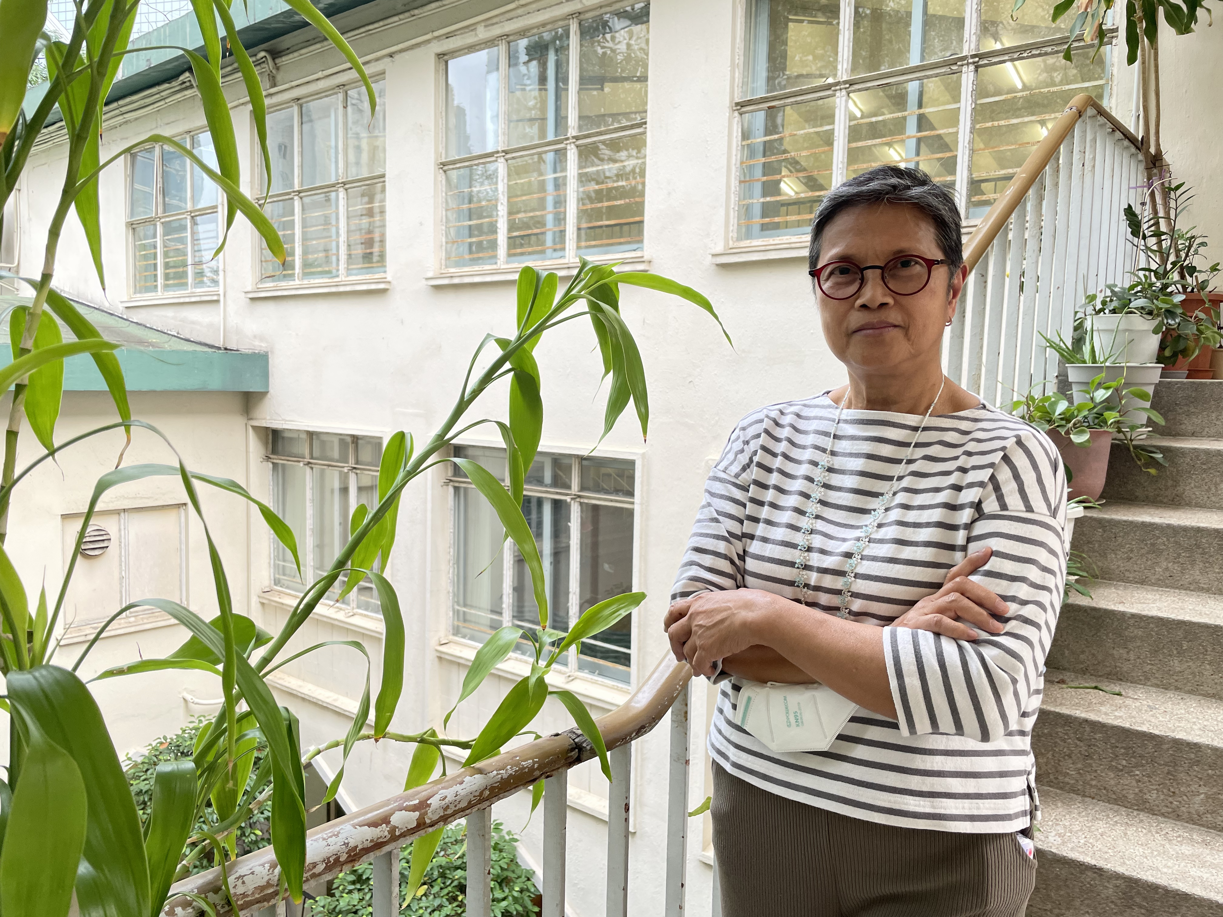 Cynthia Abdon-Tellez. She has short hair and glasses and is wearing a stripy long-sleeved jersey. She is standing outside on a walkway with a building behind her