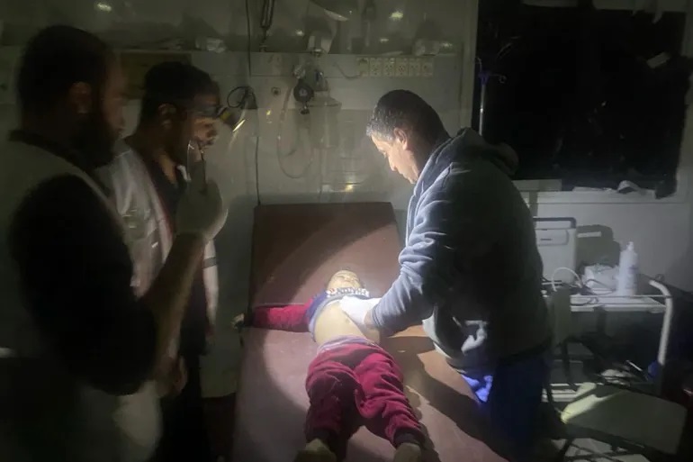 a photo of a doctor checking up on a child in darkness with another holding a flash light