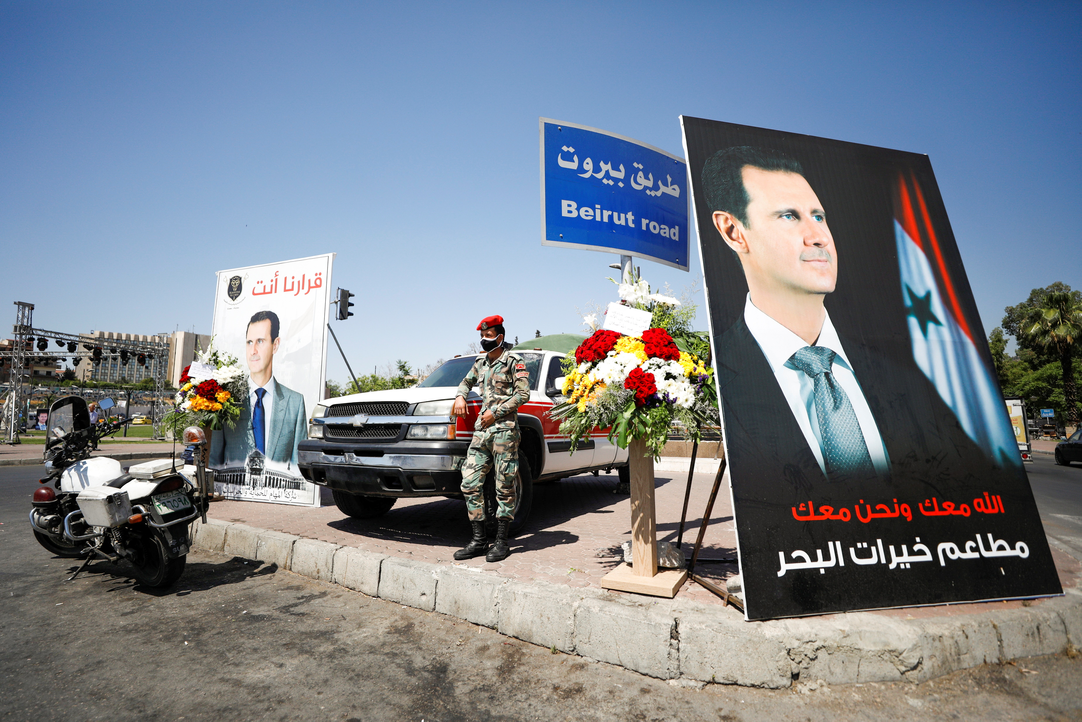 A Syrian military police officer stands near posters of Syria's President Bashar al-Assad in Damascus on May 26, 2021