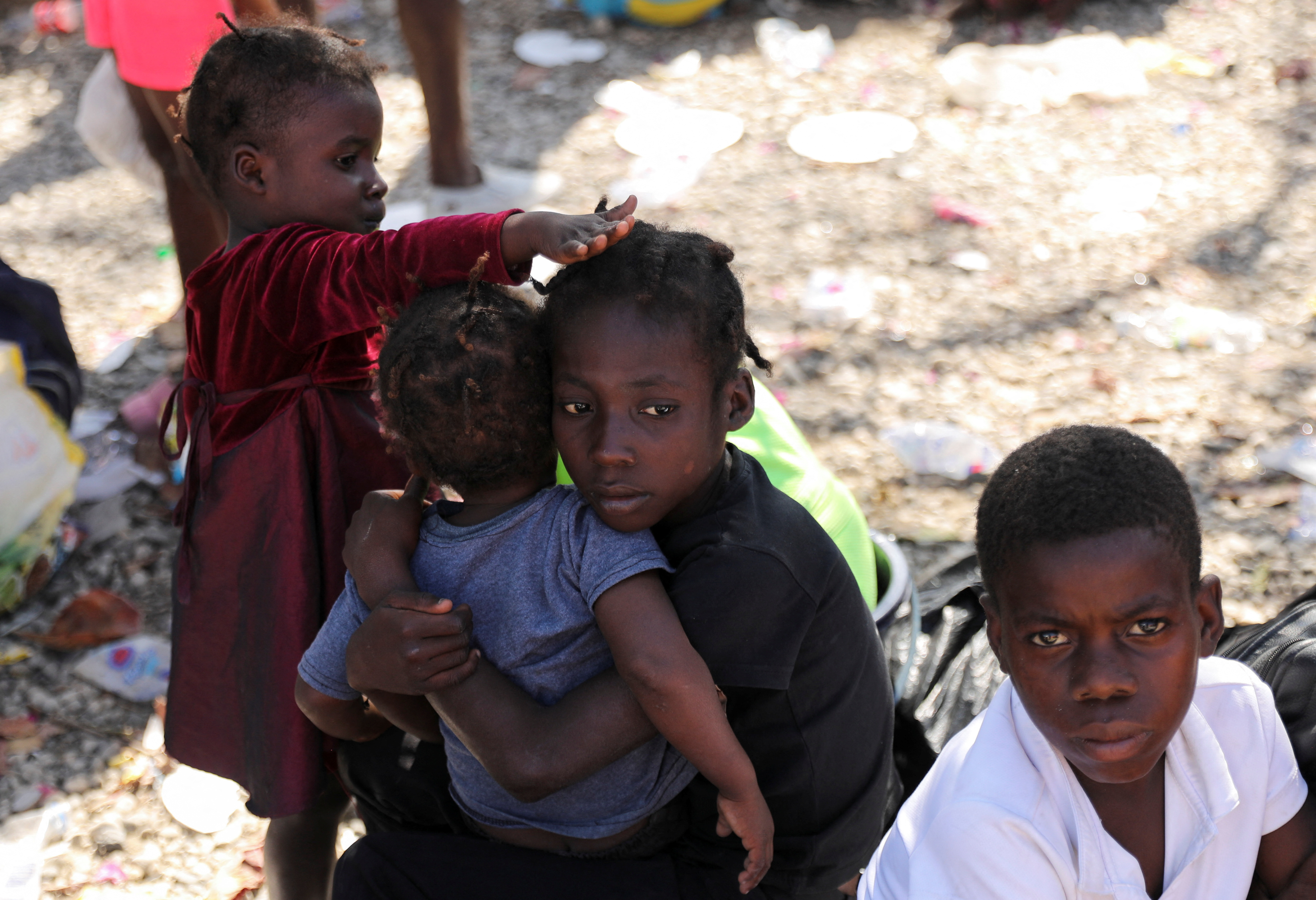 Children fleeing violence sit outside a Haitian National Police station, following a shootout between rival gangs, in Port-au-Prince, Haiti