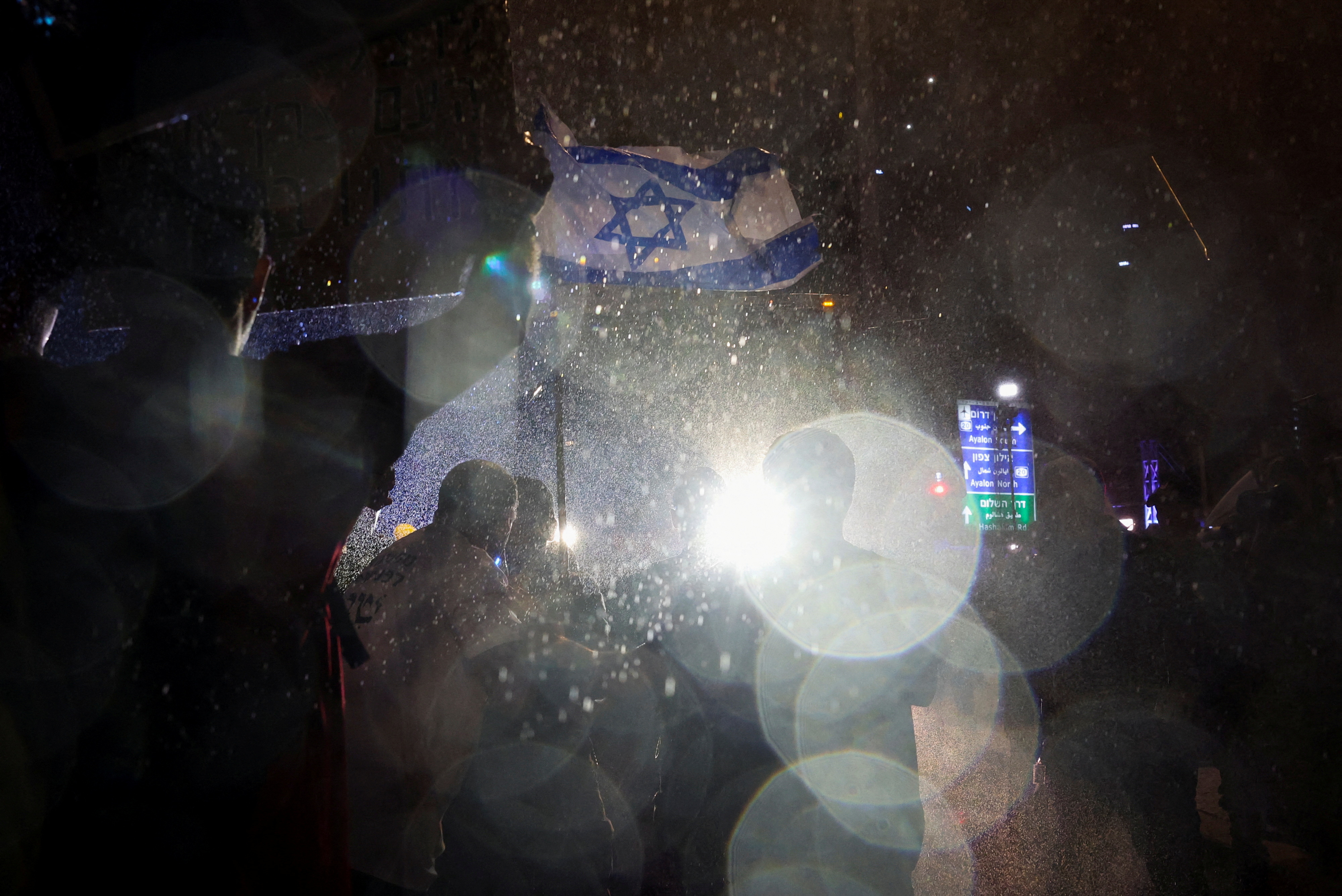 Demonstrators hold an Israeli flag and banners, as police use water cannons during a protest against Israeli Prime Minister Benjamin Netanyahu's government and to call for the release of hostages kidnapped in the deadly October 7 attack on Israel by the Palestinian Islamist group Hamas, in Tel Aviv, Israel, May 18, 2024. REUTERS/Shannon Stapleton TPX IMAGES OF THE DAY