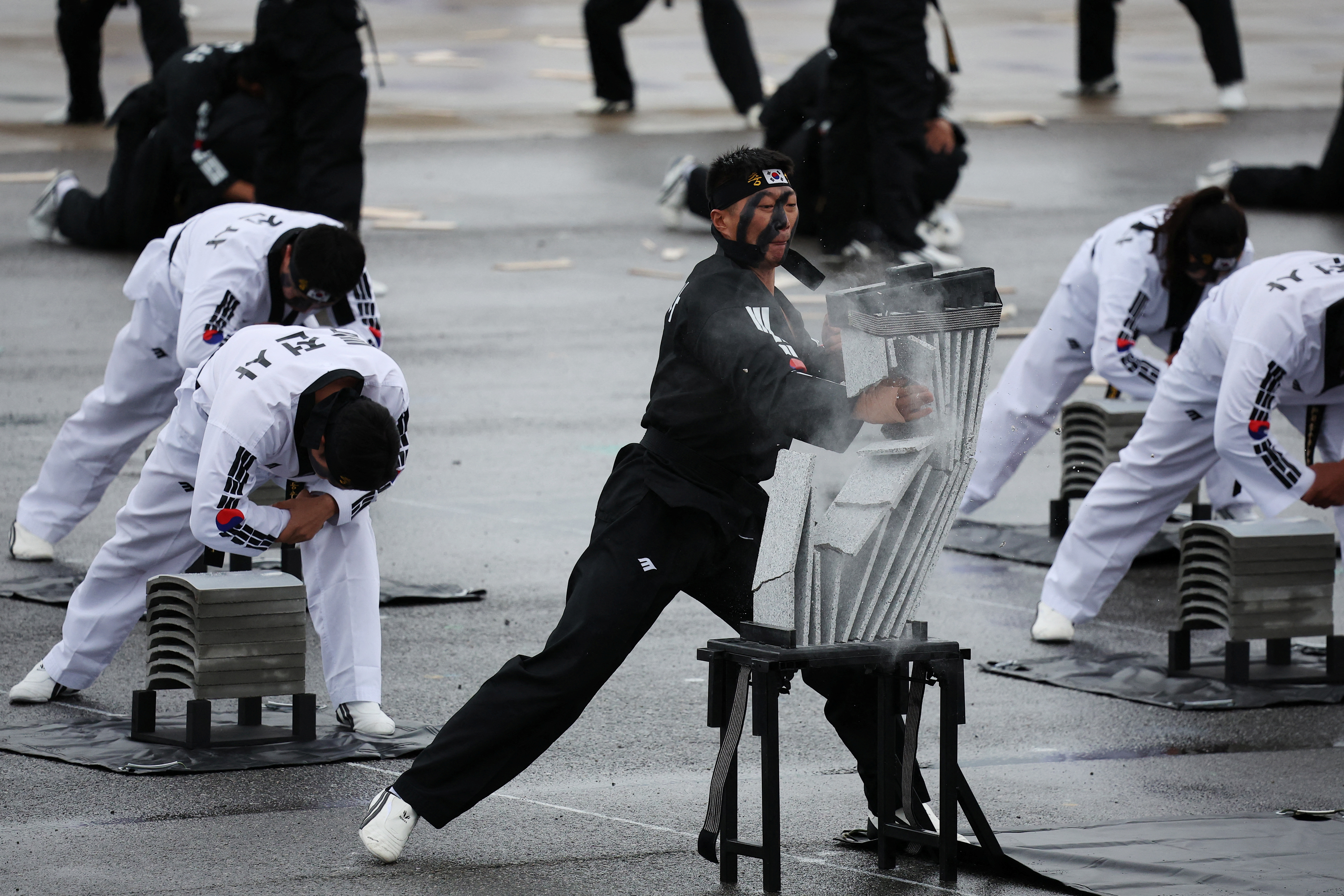 Members of the special forces showing their taekwondo skills. They are wearing white taekwondo suits and smashing concrete sheets with their hands