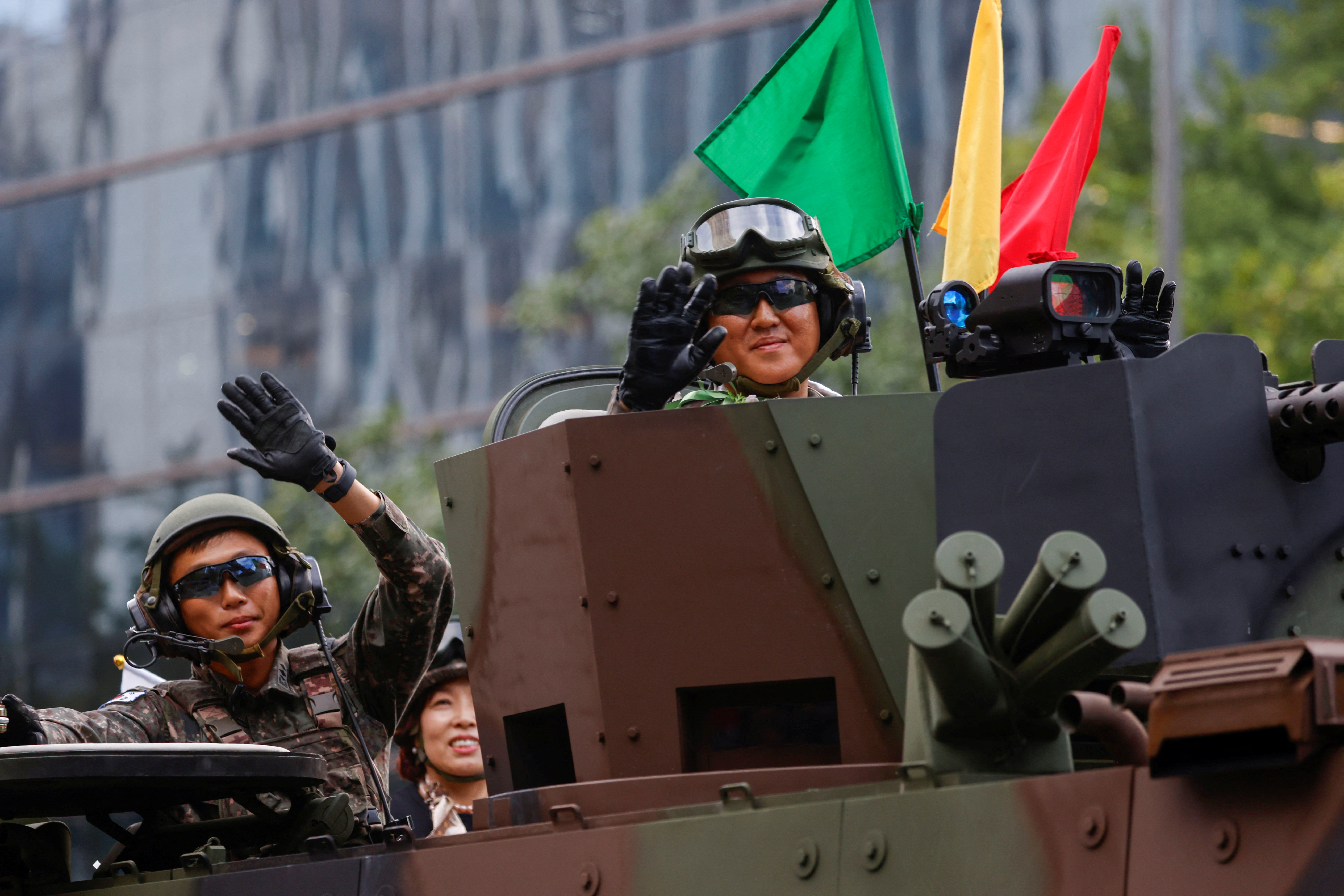 South Korean servicemen smiling and waving from a military vehicle during the parade