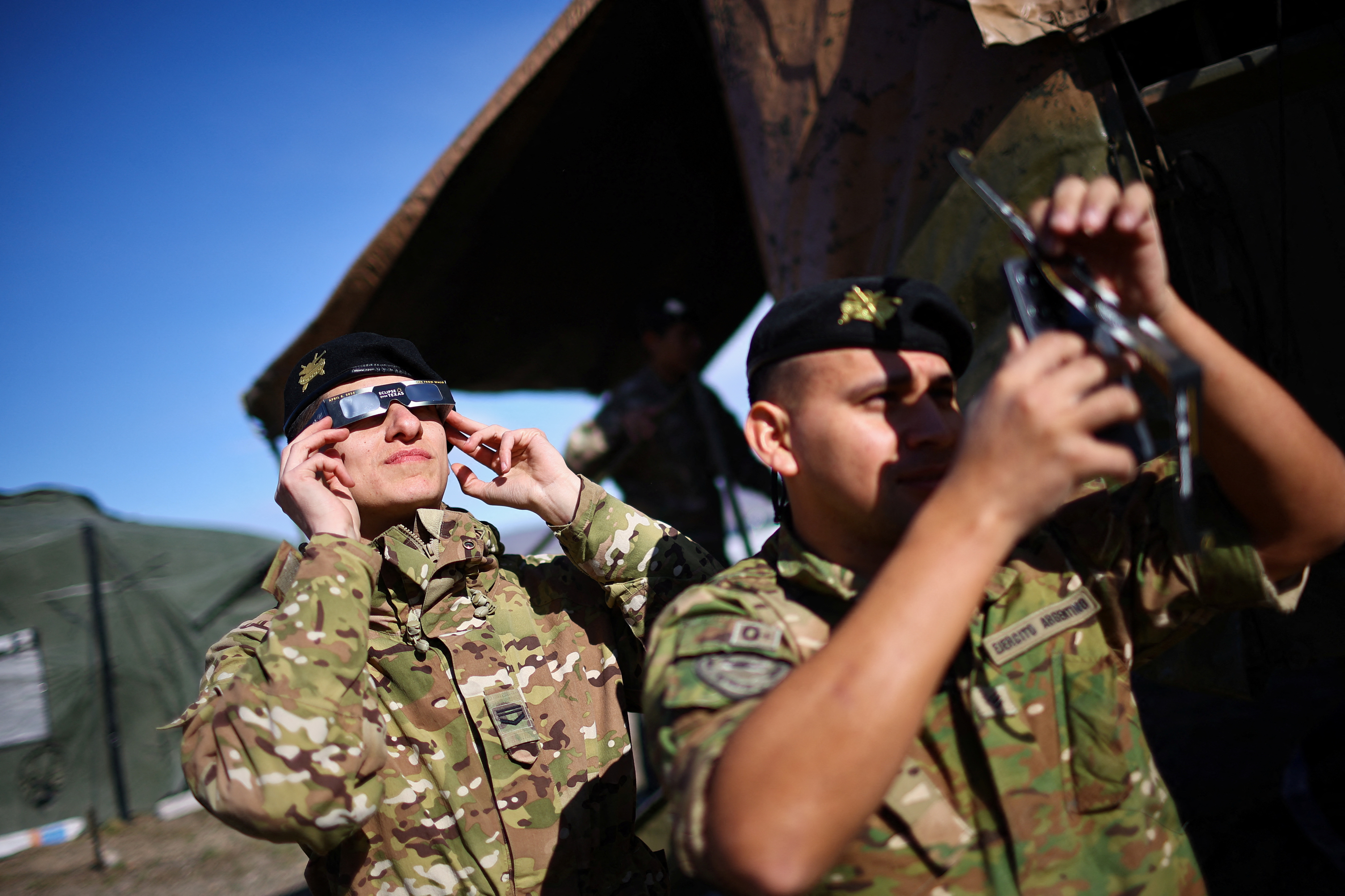 Soldiers watch the eclipse through protective glasses.