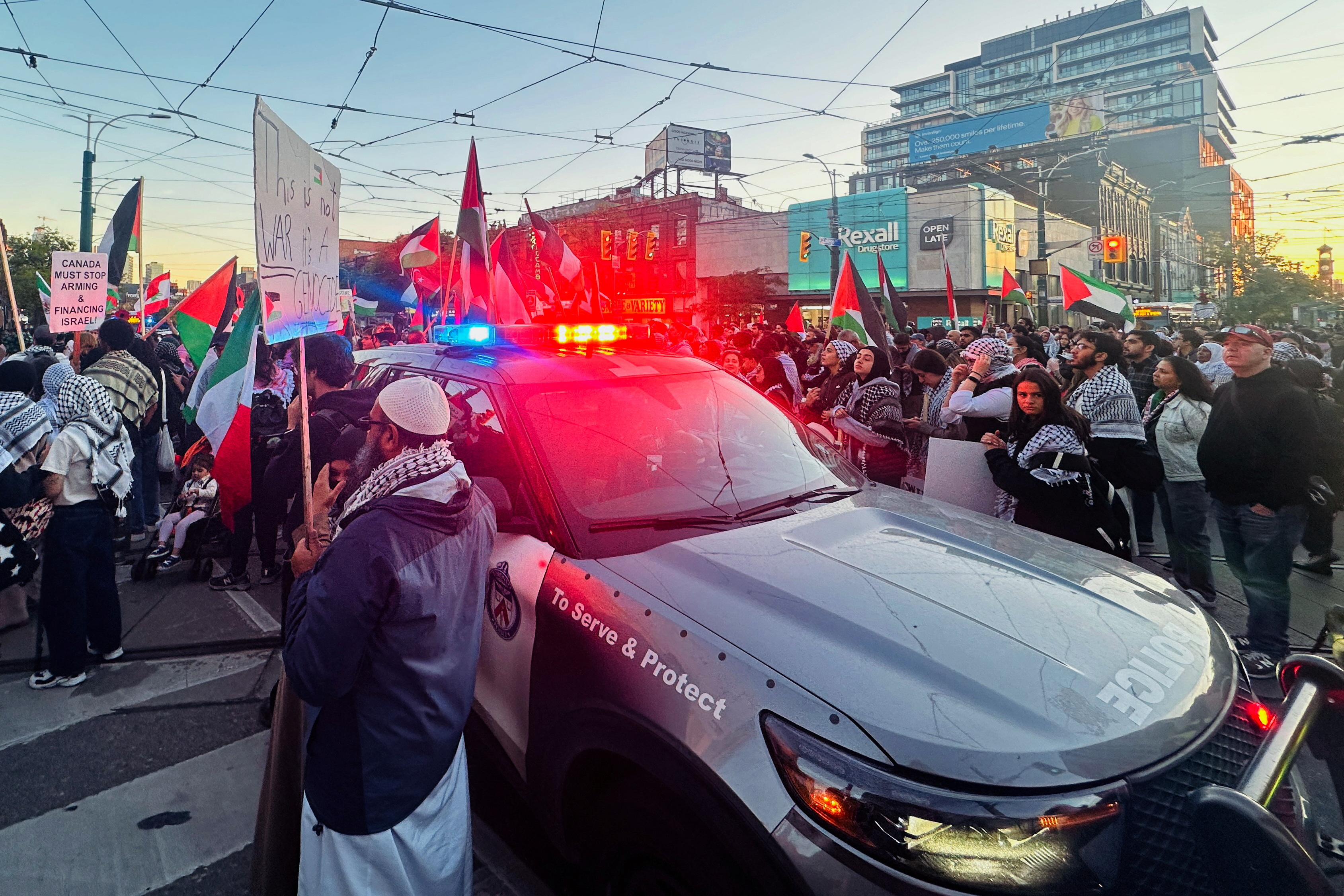 A crowd passes a police car during a protest in solidarity with Gaza in Toronto, Canada