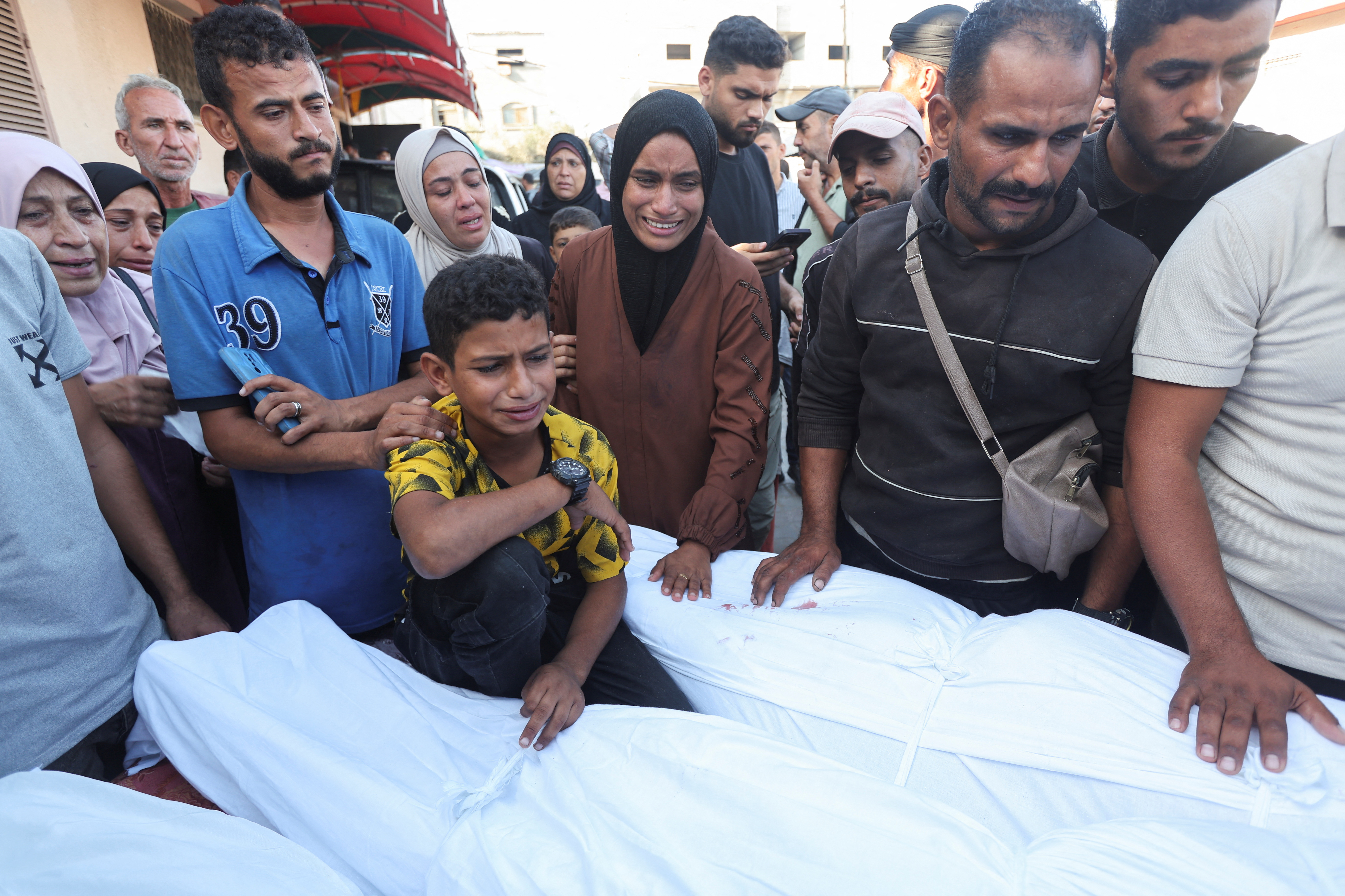 A boy mourns near the body of his father and other Palestinians, who were killed in an Israeli strike, amid the Israel-Hamas conflict, at Al-Aqsa Martyrs Hospital