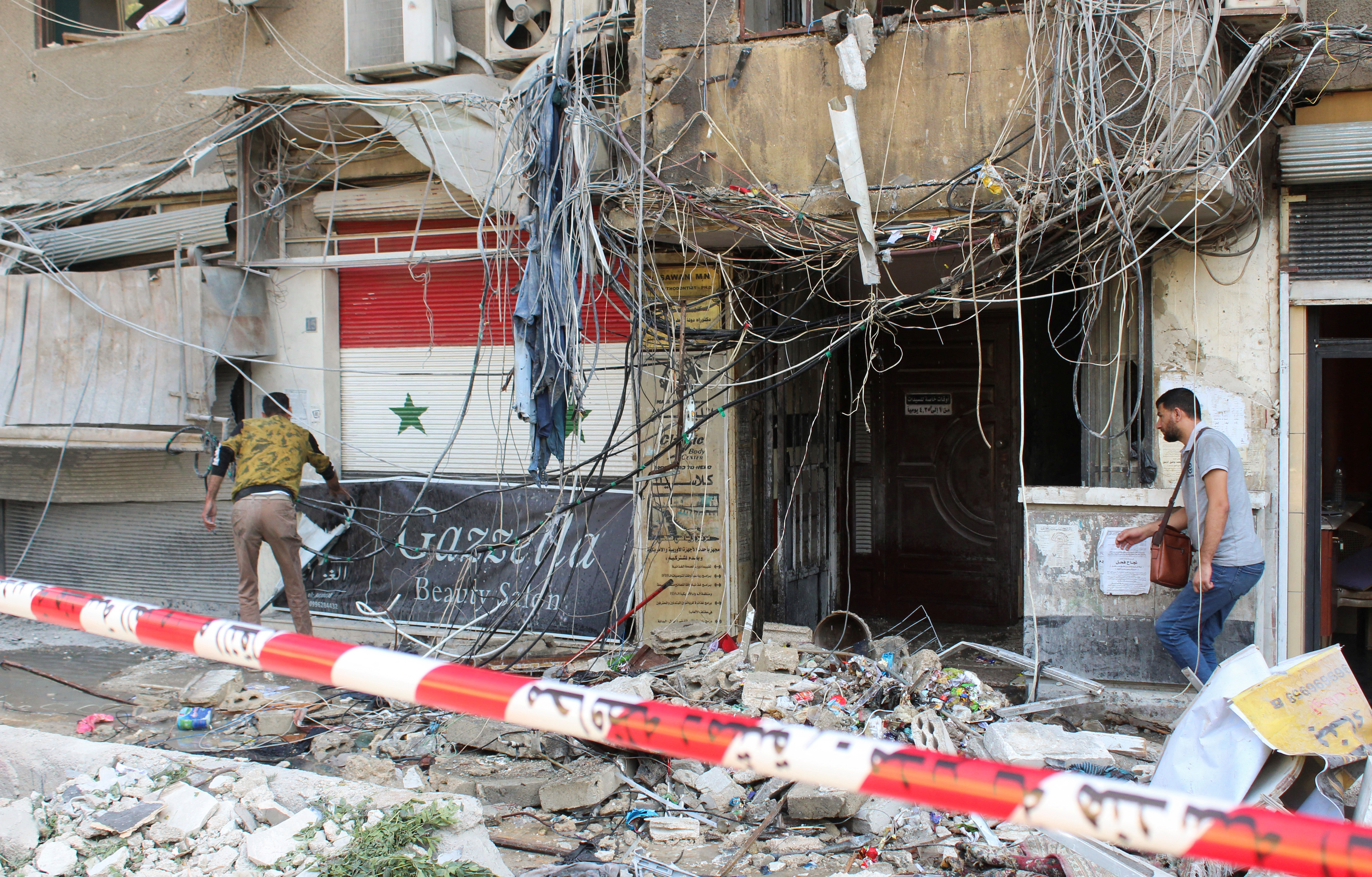 People inspect a damaged area in the aftermath of what Syrian state media reported was an Israeli strike in the Mezzah suburb